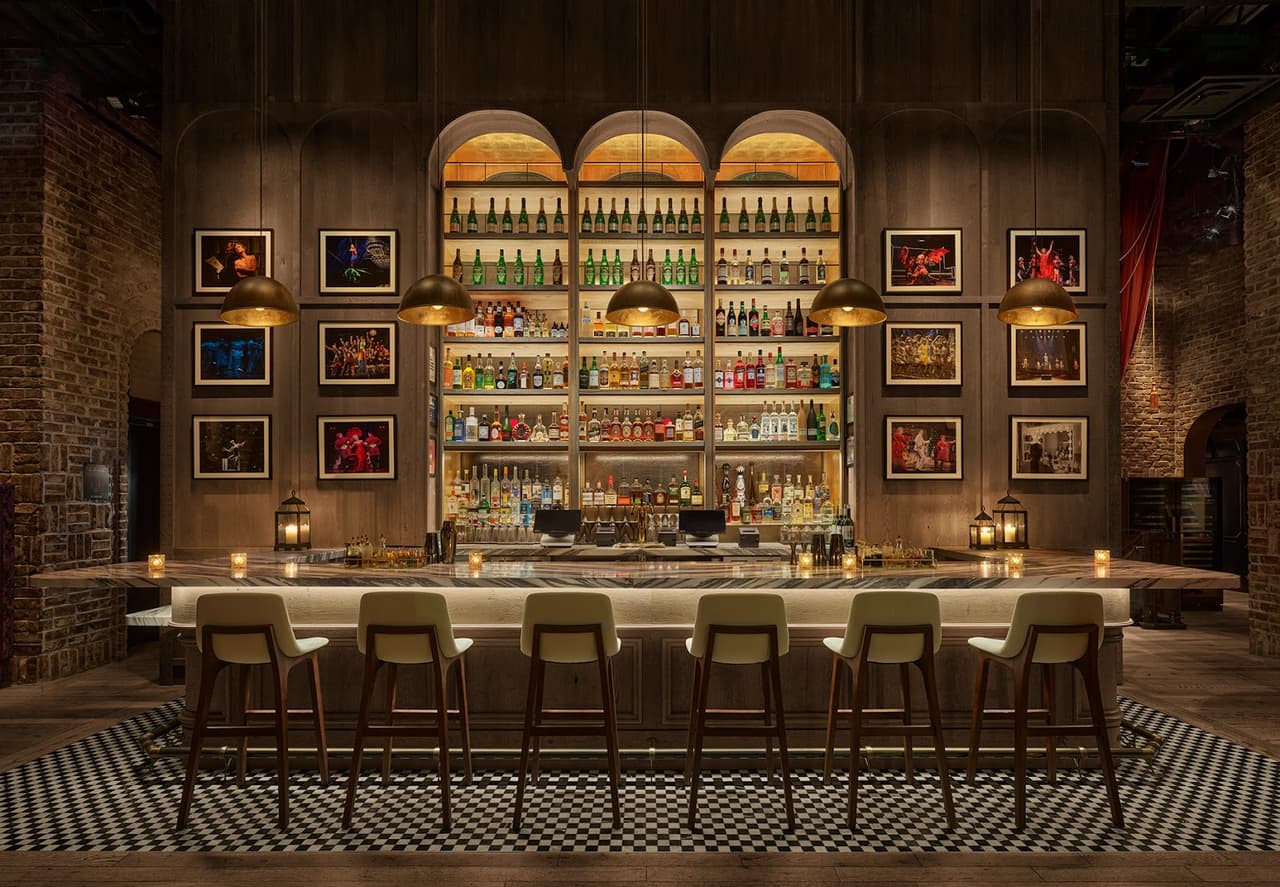 Elegant bar with well-lit shelves of bottles and chic bar stools