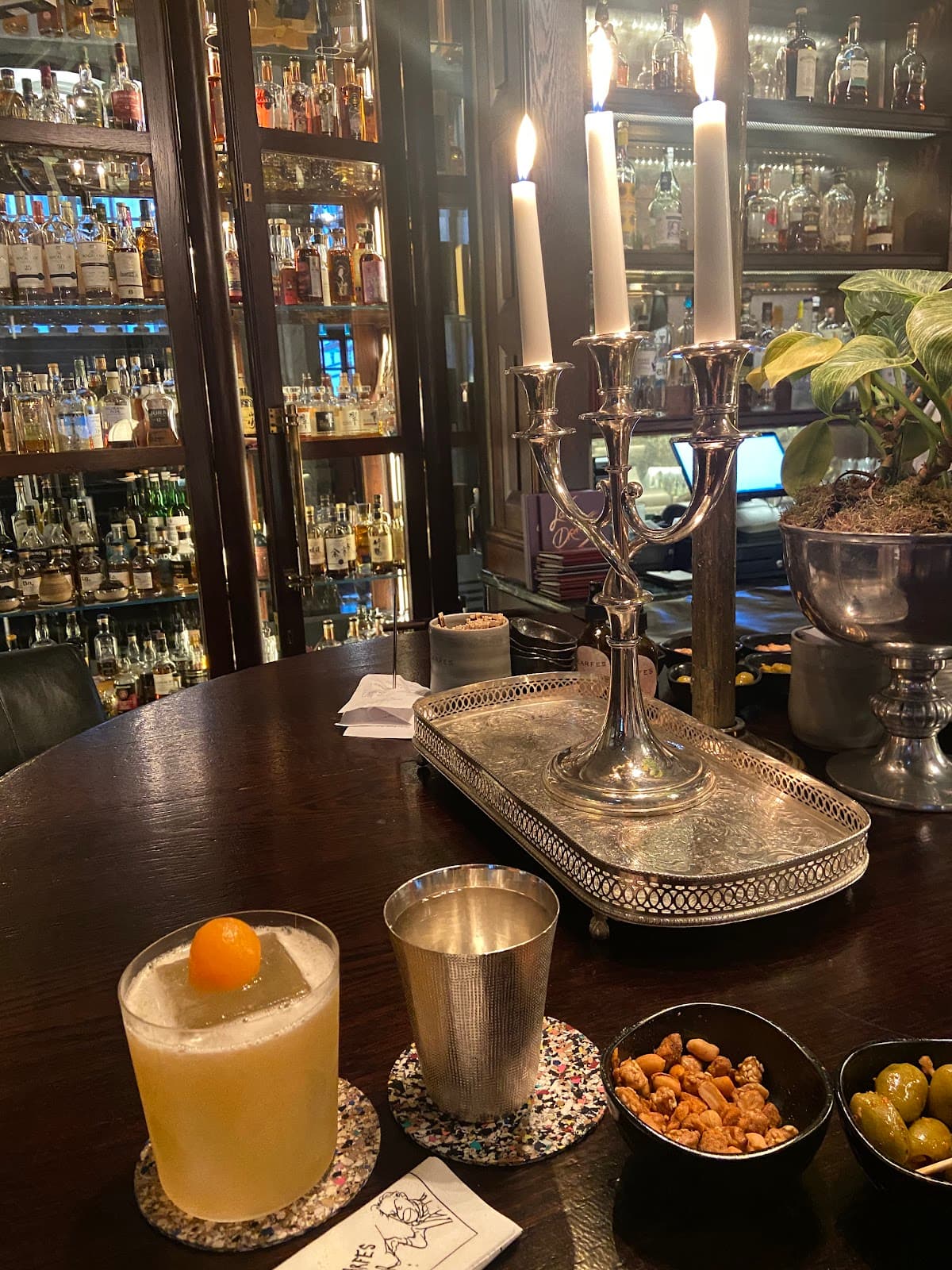 Elegant bar setup with a cocktail, snacks, and a candelabra in London