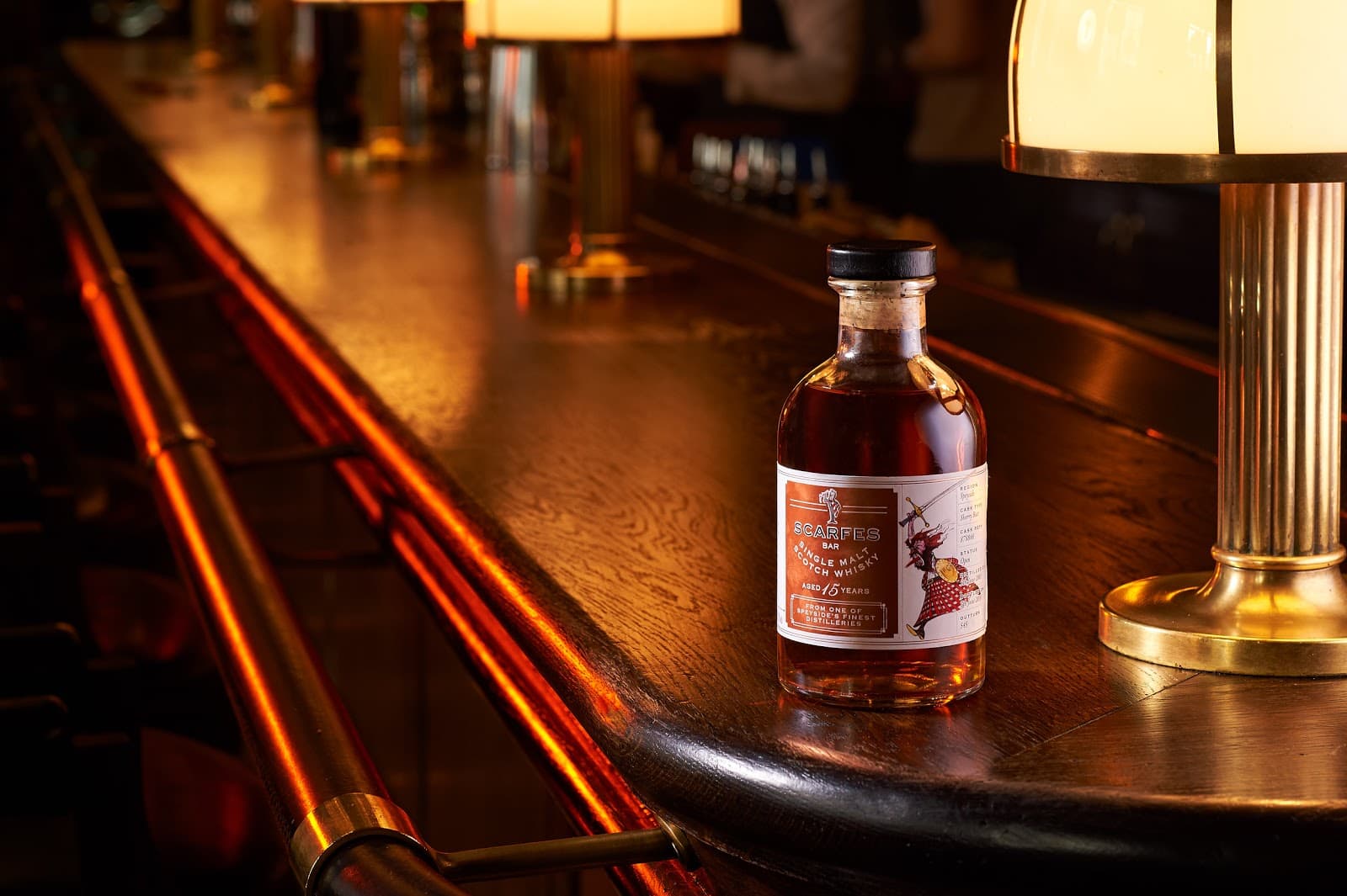Bottle of whisky on a dimly lit bar counter with warm lighting in London