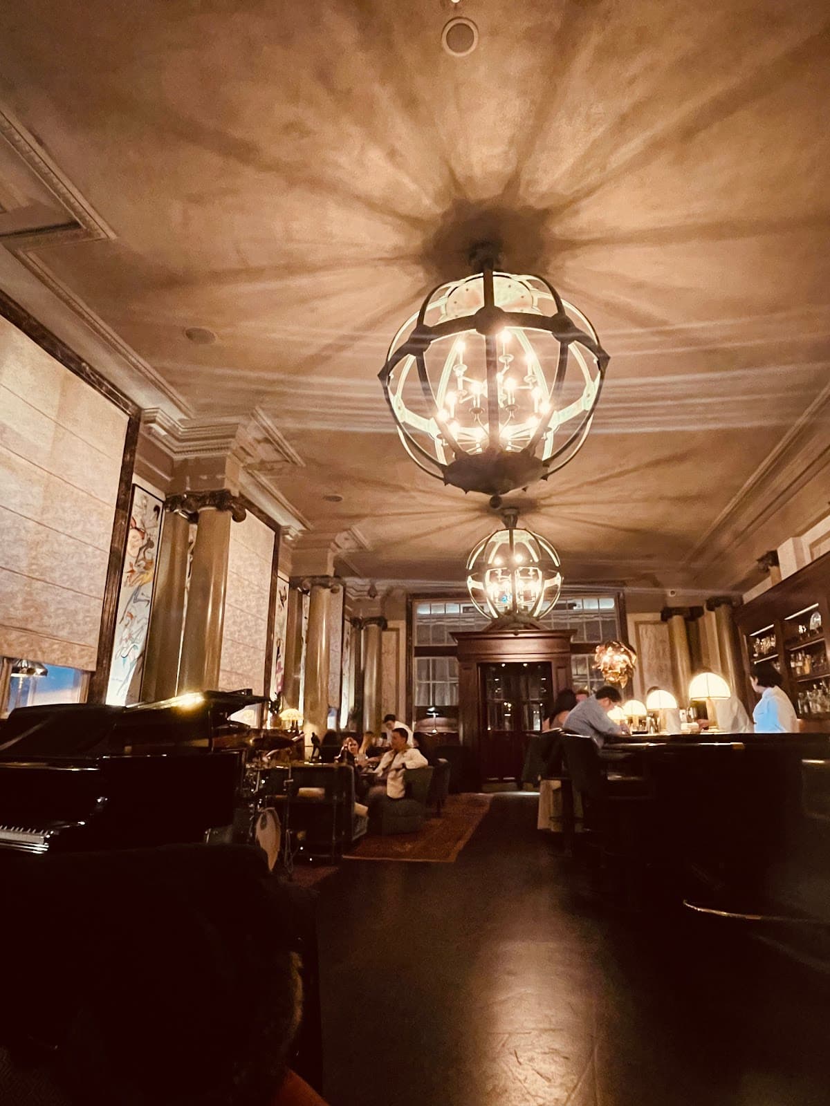 Elegant cocktail bar interior with chandeliers and patrons seated in London