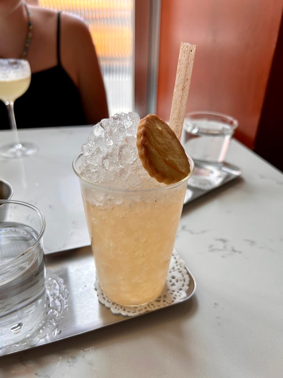 Cocktail with ice, cookie, and stick garnish on a table in New York