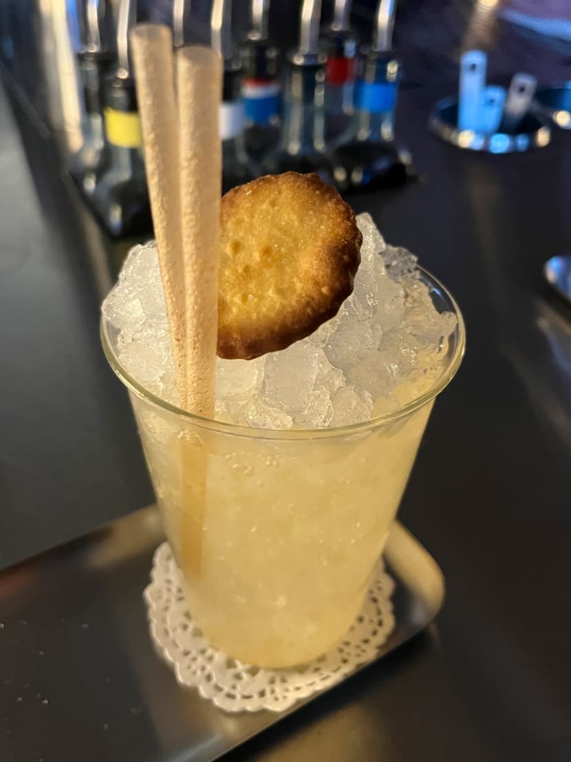 Cocktail with ice and a cookie garnish on a bar counter in New York