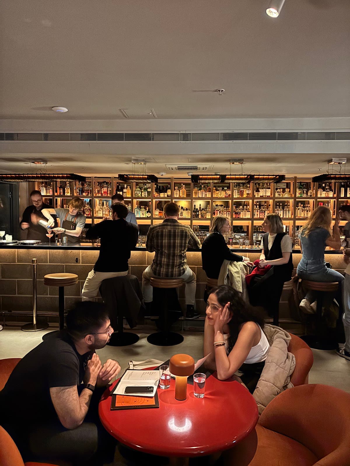 People seated at a lively bar with a well-stocked backdrop in London