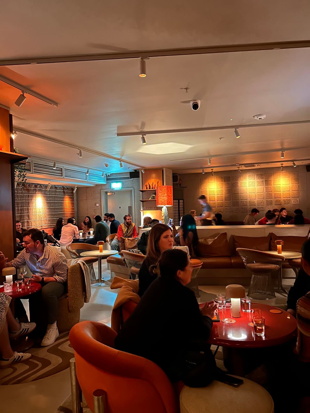 Modern bar interior with patrons seated at tables in warm lighting in London