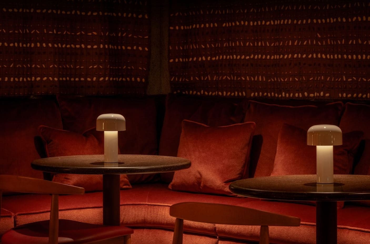 Cozy interior with warm lighting, round tables, and plush seating in London