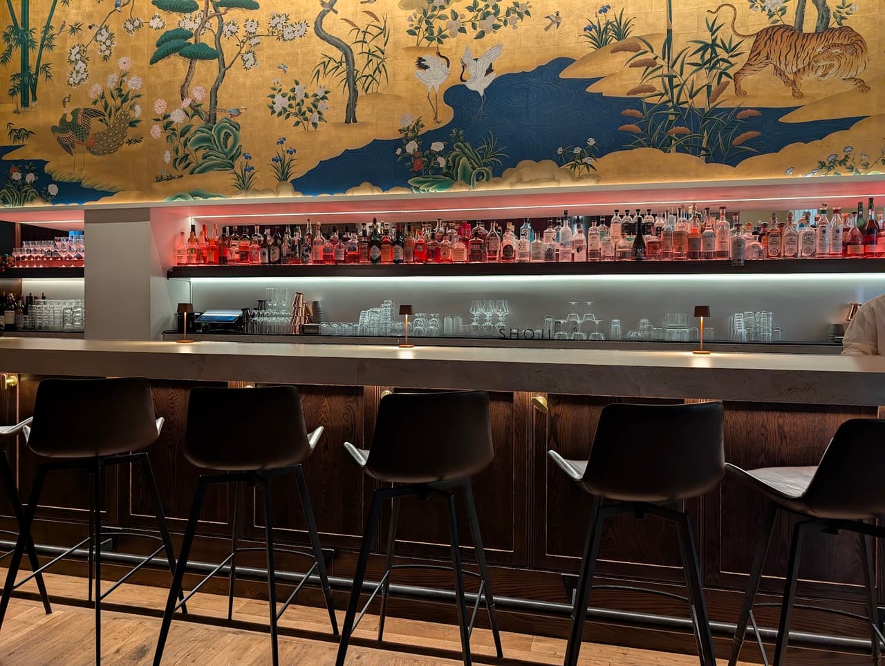Chic bar with high chairs, vibrant mural, and well-stocked shelves in San Francisco