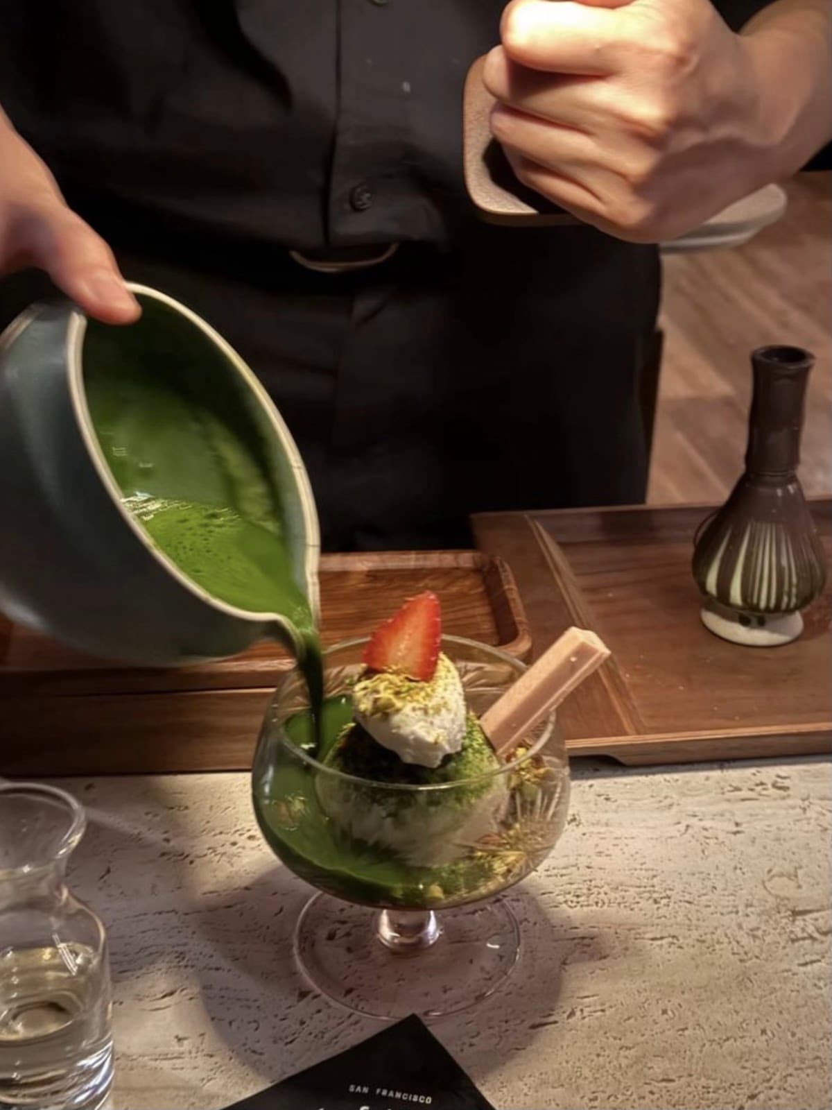 Bartender pouring green liquid over a dessert in a glass in San Francisco