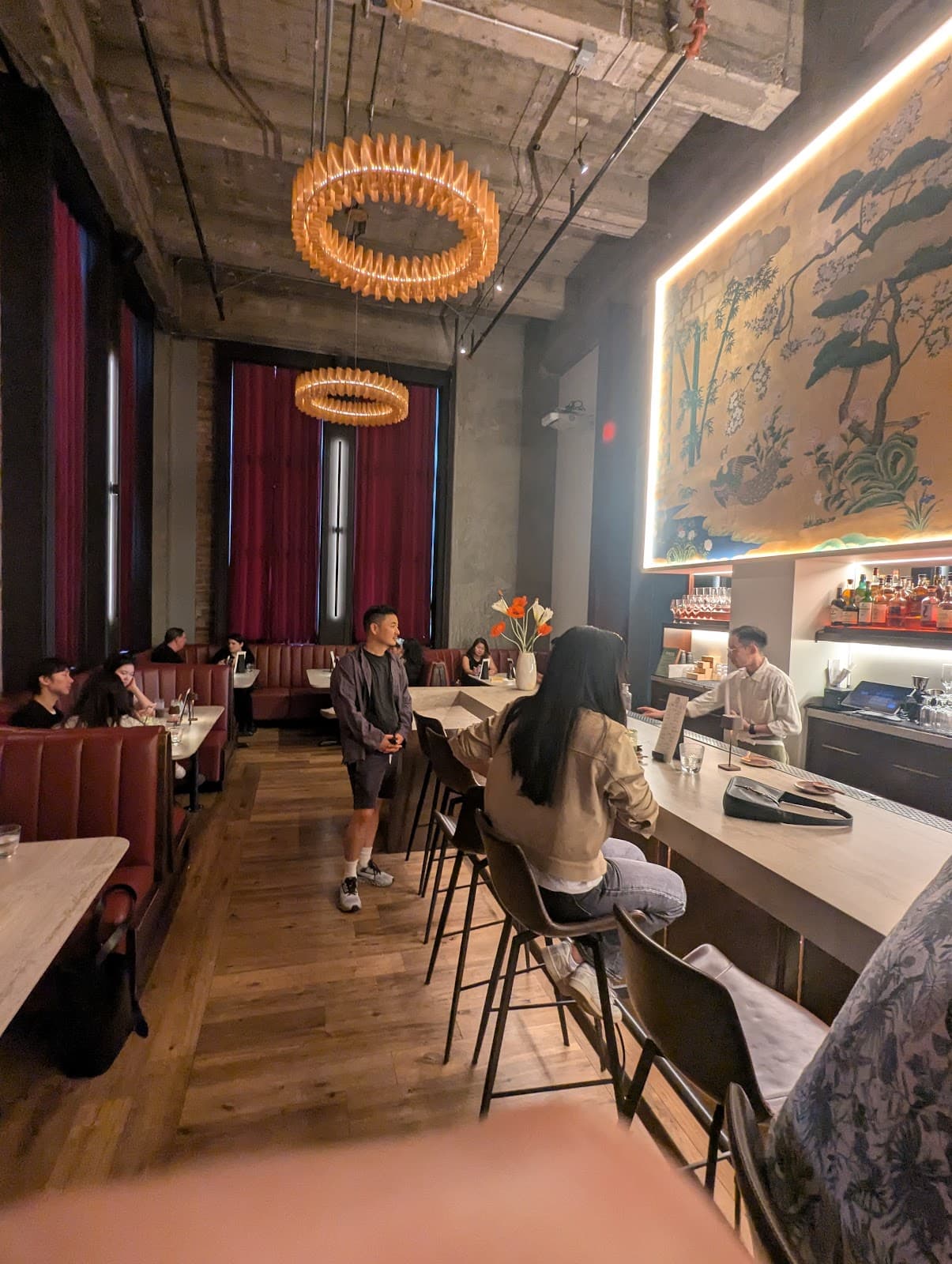 Chic bar interior with high ceilings, modern lighting, and patrons at the counter