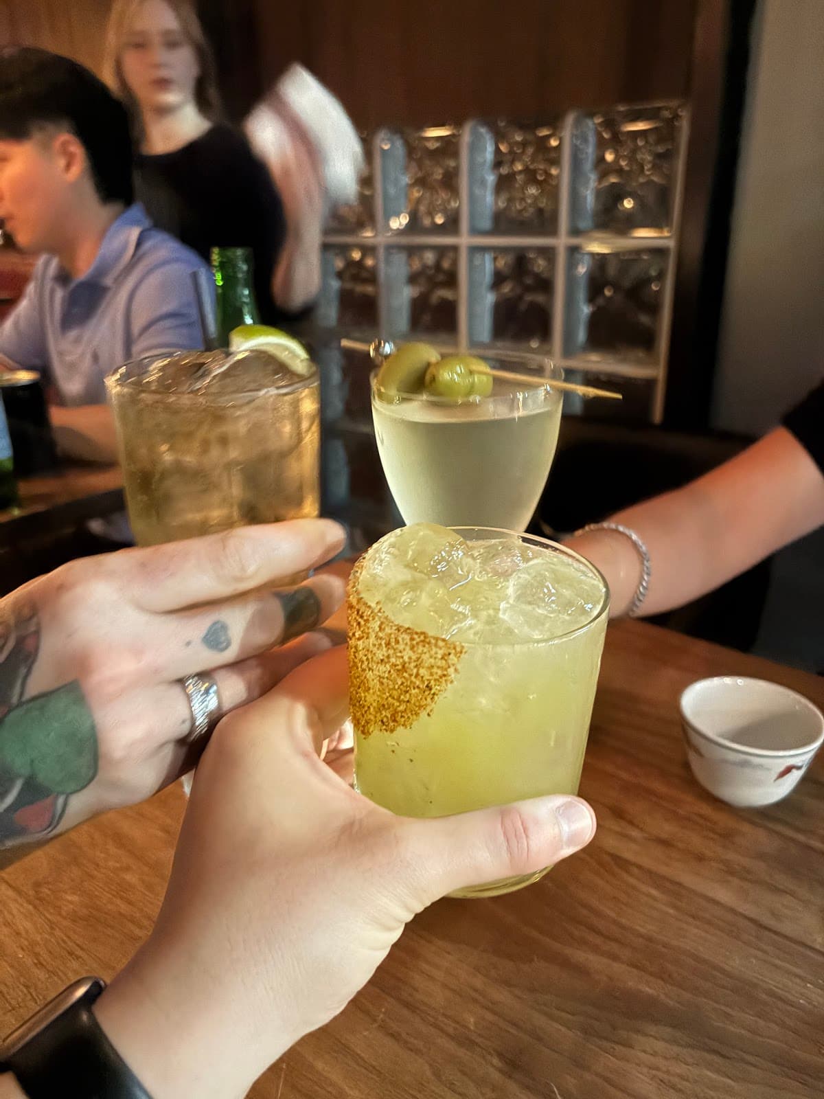 Close-up of people toasting with three cocktails at a bar in Toronto