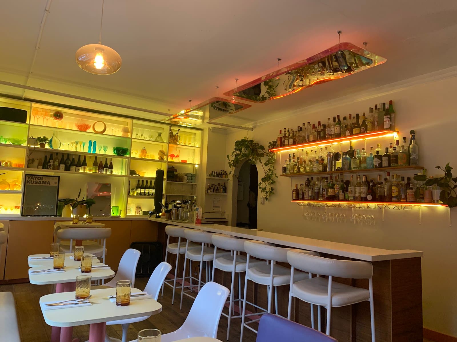 Modern bar interior with colorful backlit shelves and white bar stools