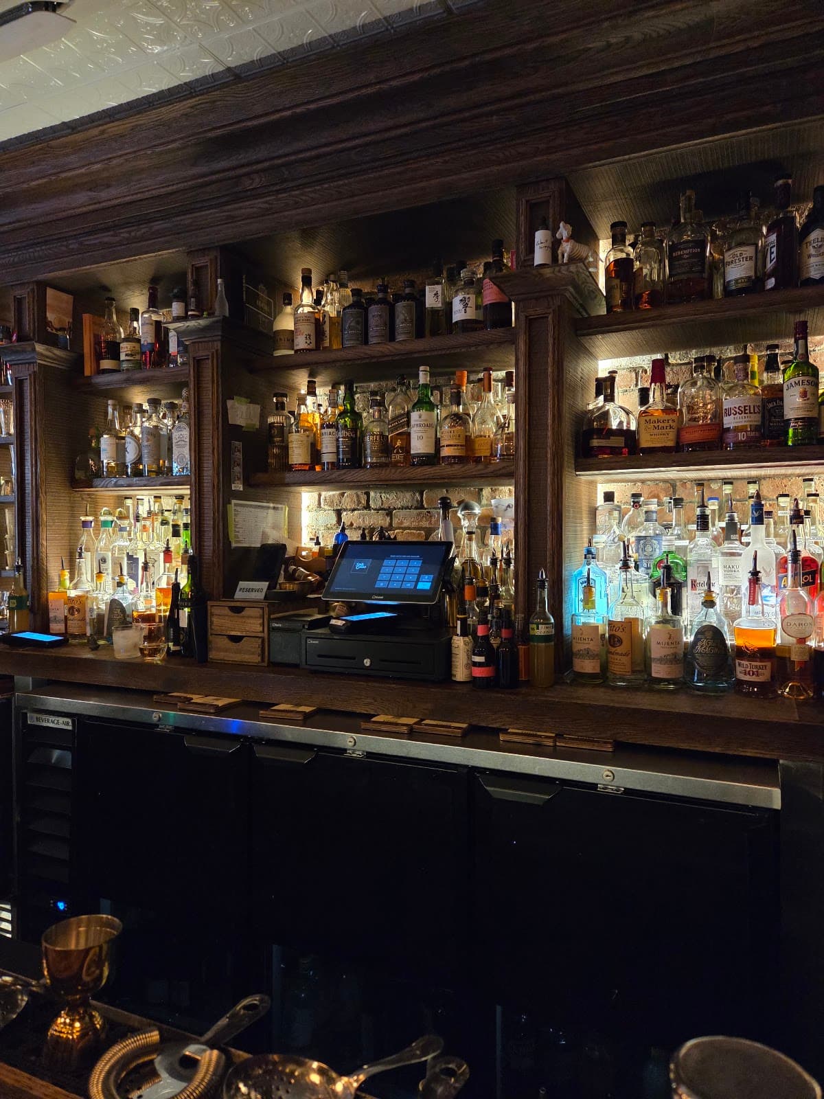 Close-up of a well-stocked bar with liquor bottles and cash register in New York