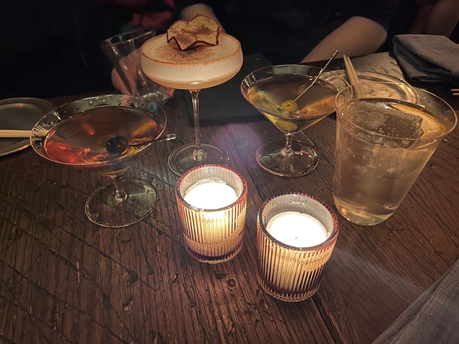Assorted cocktails on a wooden table with candlelight. in New York