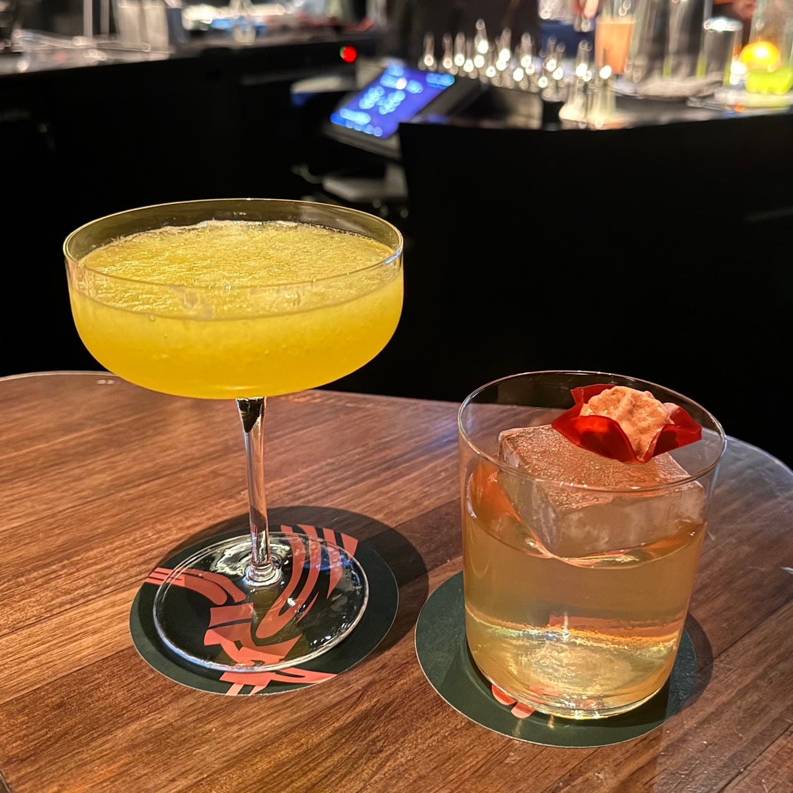 Two elegant cocktails on a wooden table in a dimly lit bar in Barcelona
