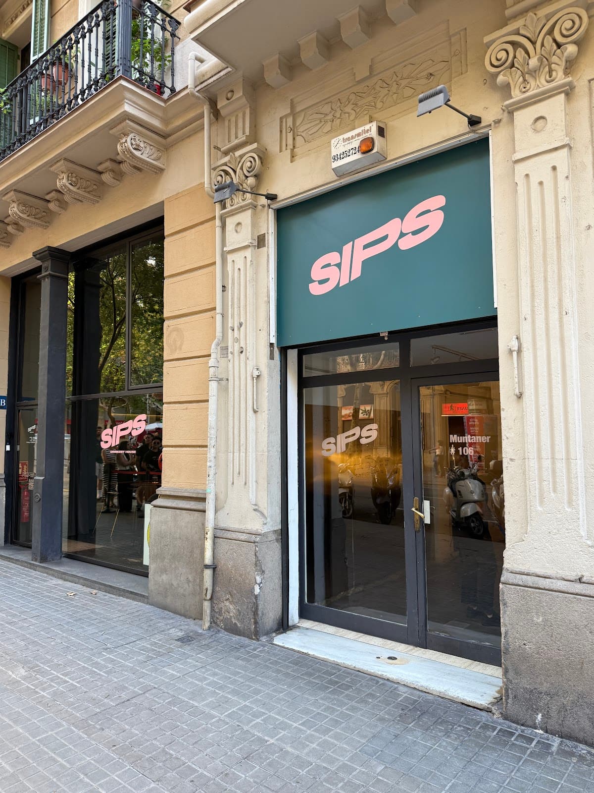 Exterior entrance of SIPS cocktail bar with ornate facade and green sign in Barcelona