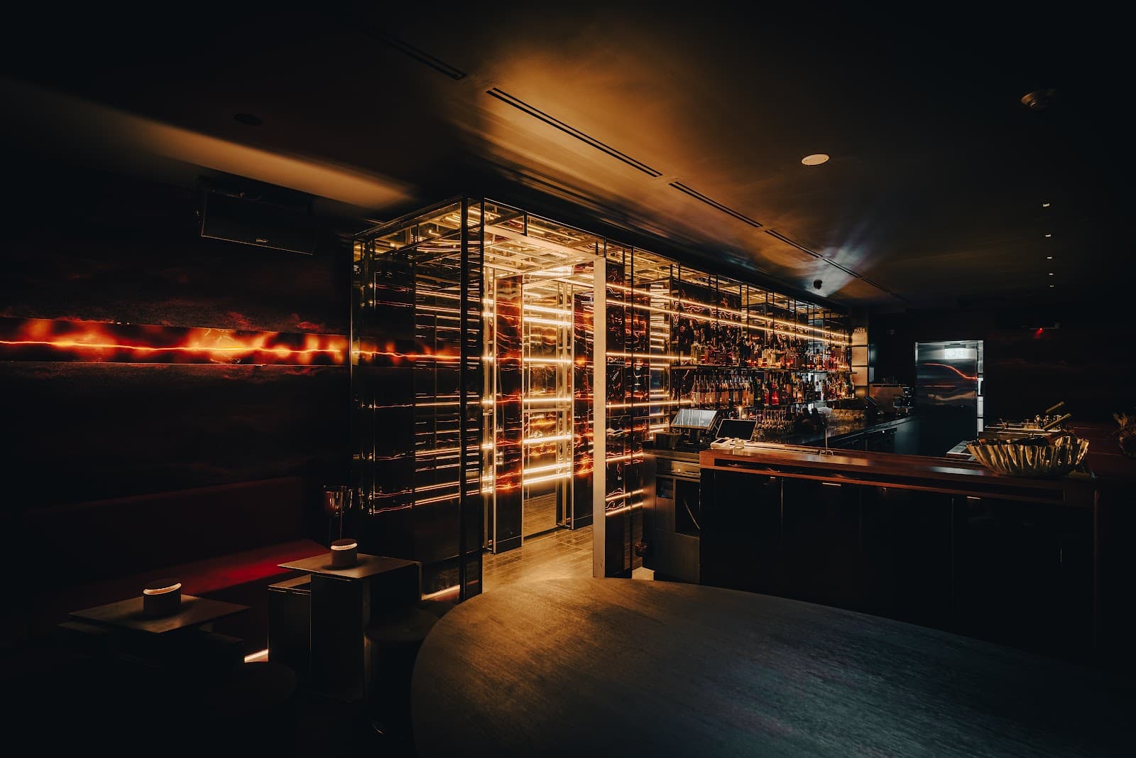Dimly lit bar with illuminated shelves and a sleek countertop in Toronto