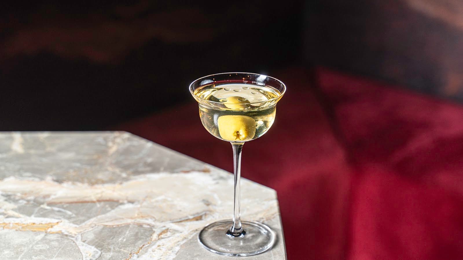 Cocktail glass with olive on a marble table in Toronto