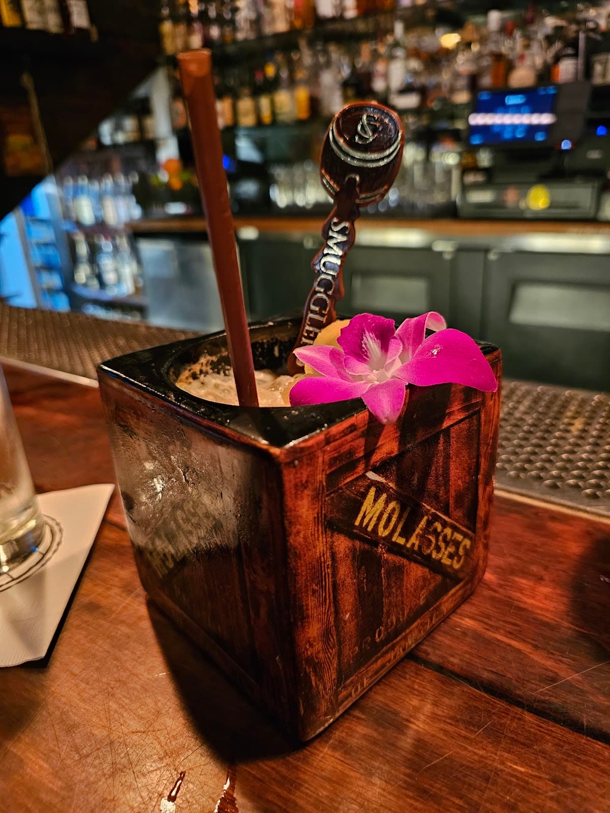 Creative cocktail served in a molasses tin with a pink flower garnish in San Francisco
