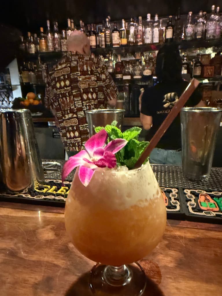 Colorful cocktail with flower garnish at a bar with bottles in background in San Francisco