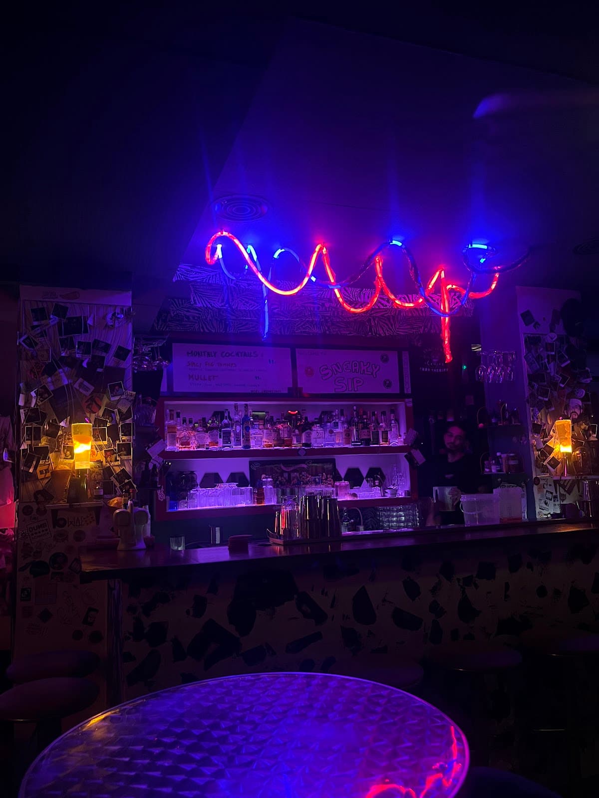 Neon-lit bar with colorful lights and shelves of bottles