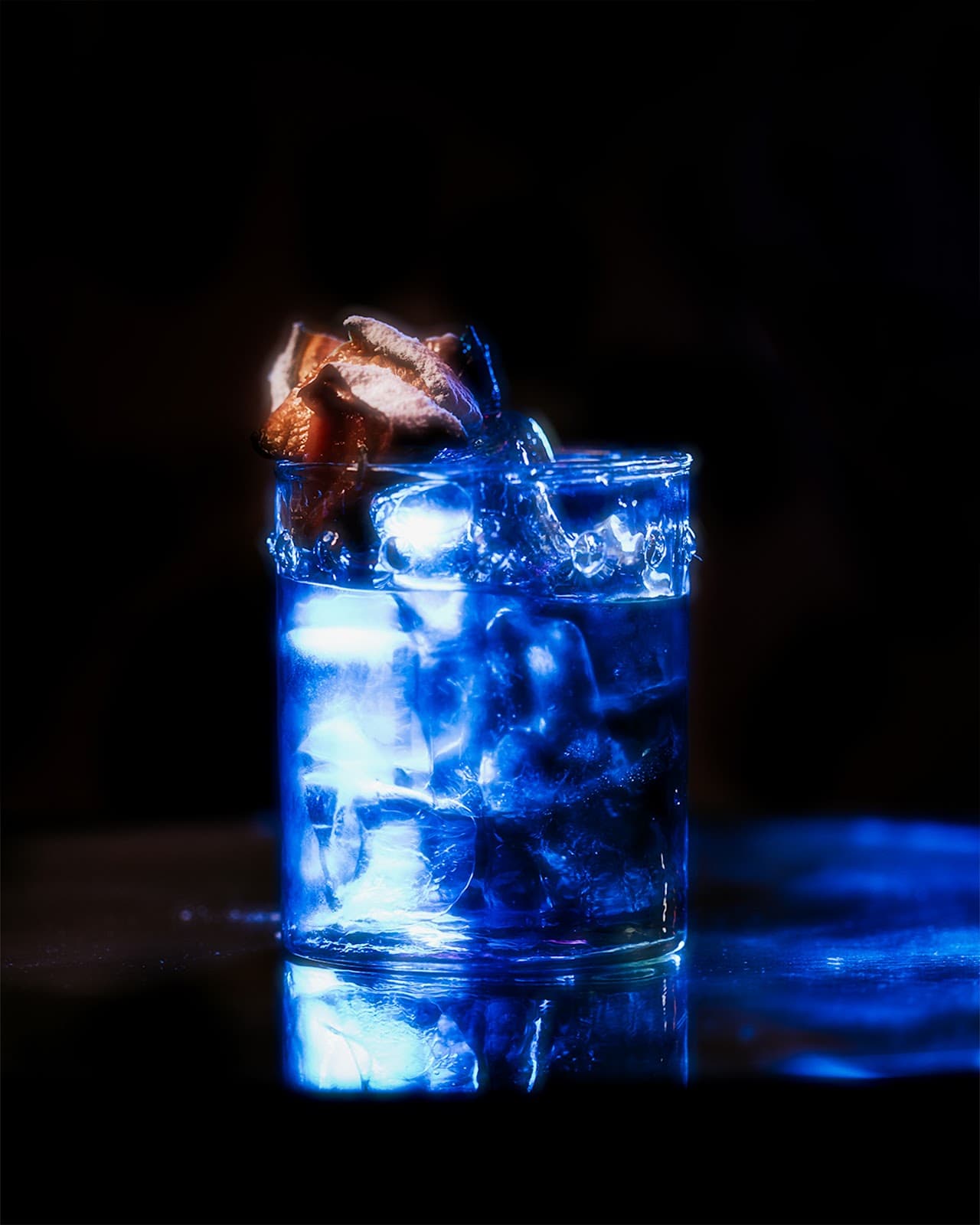 Close-up of a cocktail with ice and garnish in dramatic blue lighting in Lisboa