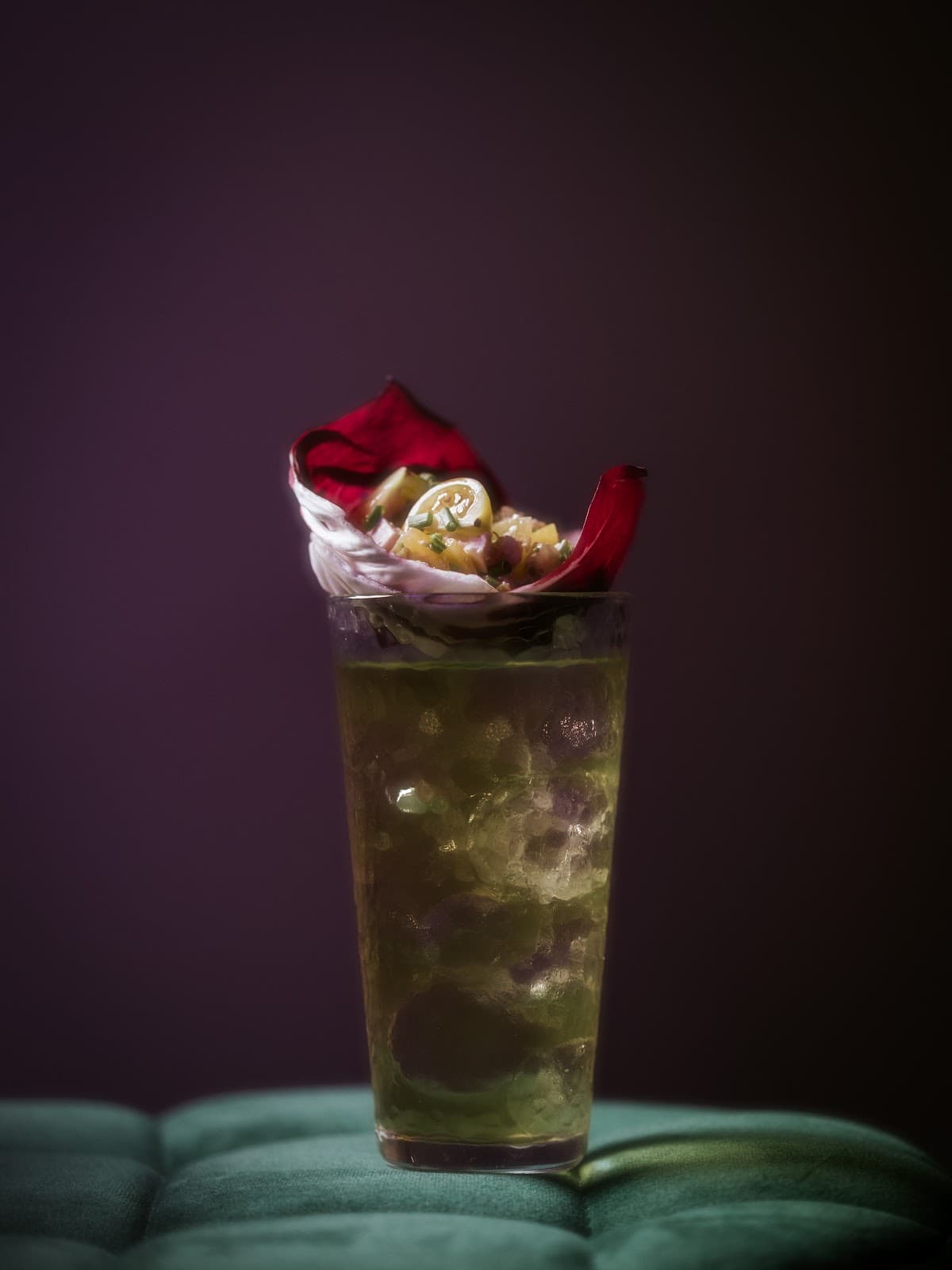 Artistic cocktail with red garnish on a tufted surface in Lisboa