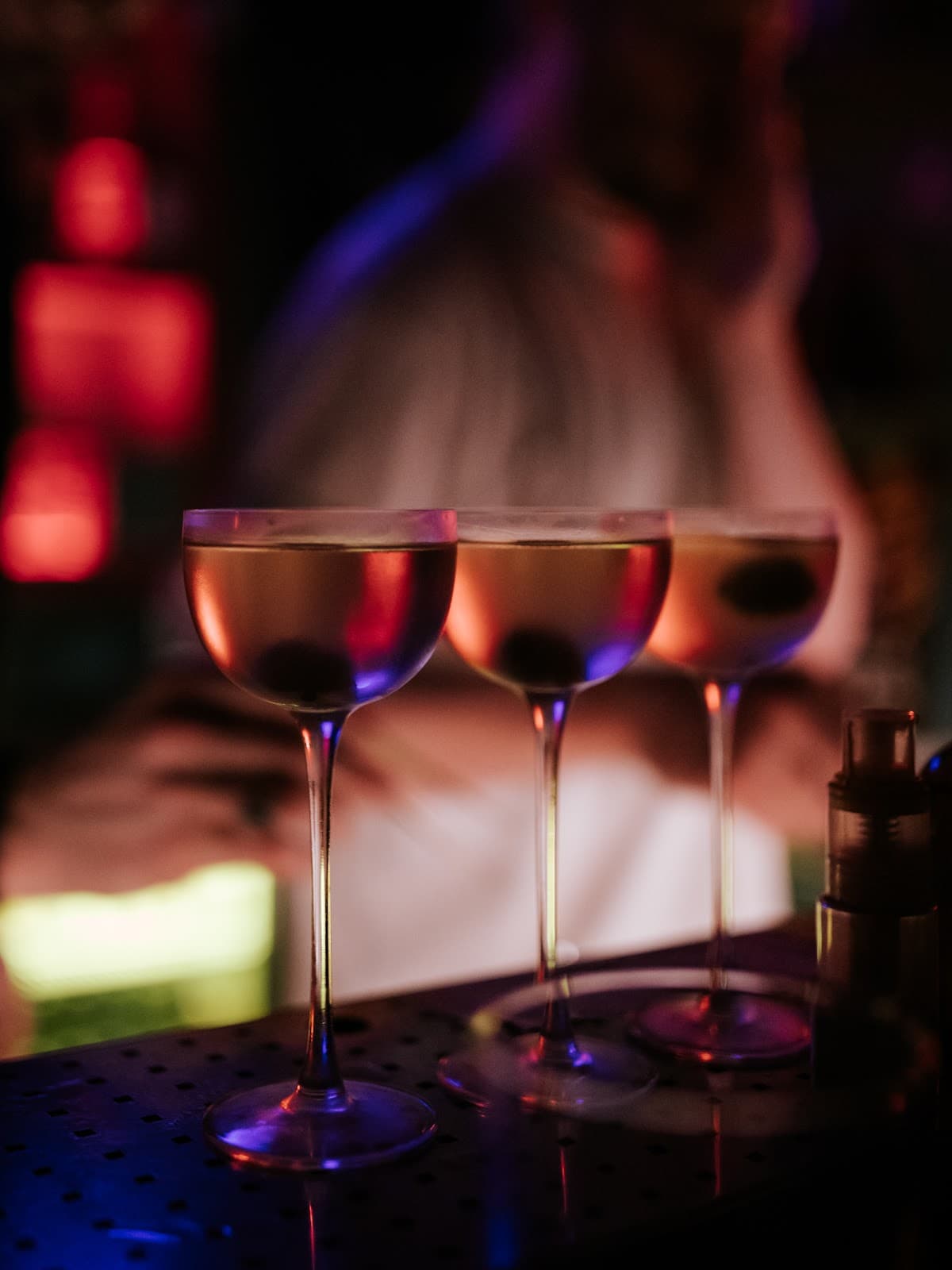 Three cocktails on a bar with colorful lighting in Lisboa
