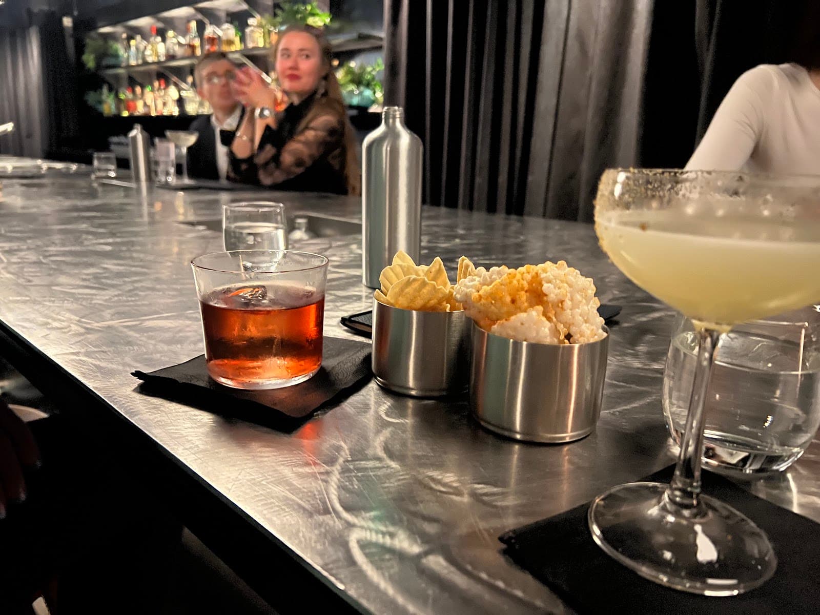 Close-up of a bar counter with cocktails and snacks in London