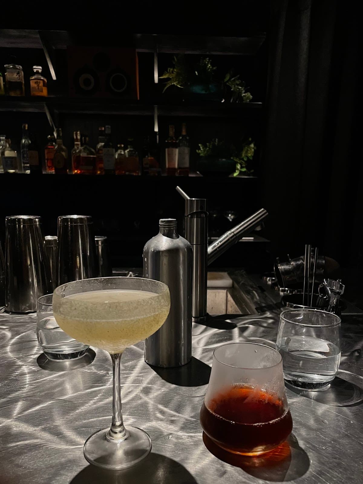 Close-up of two cocktails on a bar with bottles in the background in London