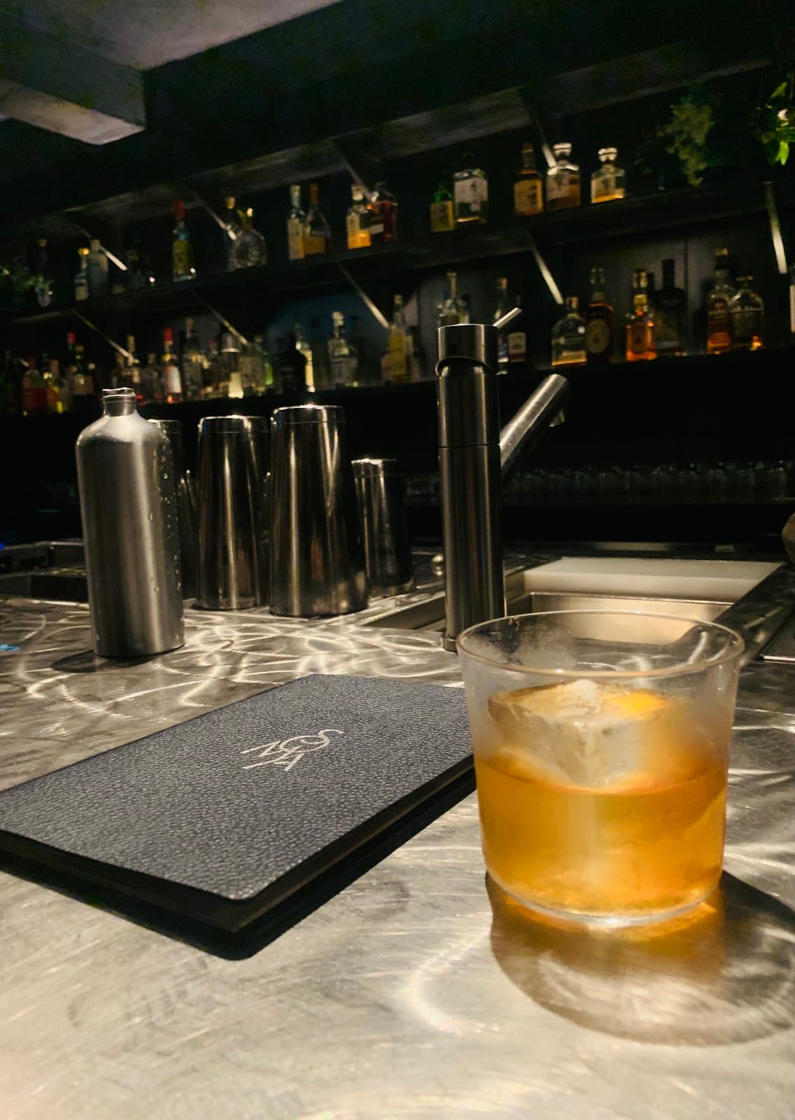 Close-up of a bar counter with a cocktail and shakers on a metallic surface in London