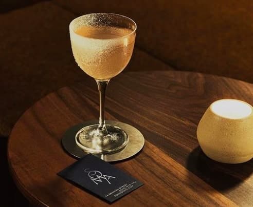 Elegant cocktail with a frosted rim on a wooden table next to a candle in London