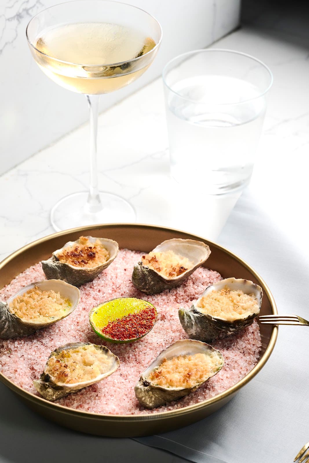 Champagne glass with oysters on pink salt in a premium bar setting in San Francisco