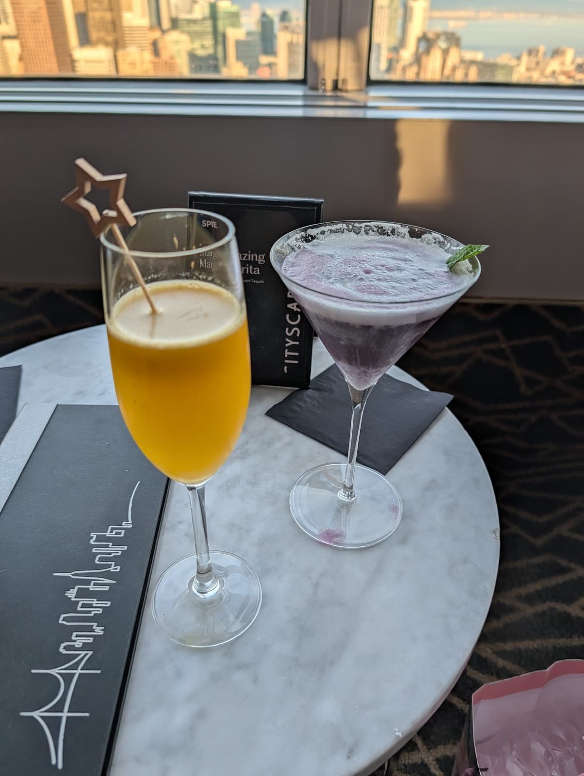 Two cocktails on a marble table with a city skyline view in San Francisco