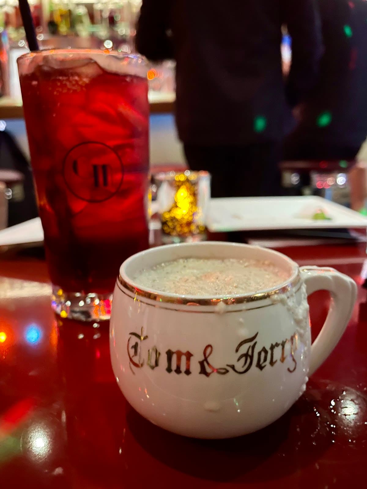 Cocktails on a bar, featuring a Tom and Jerry mug and a red drink in a glass in San Francisco