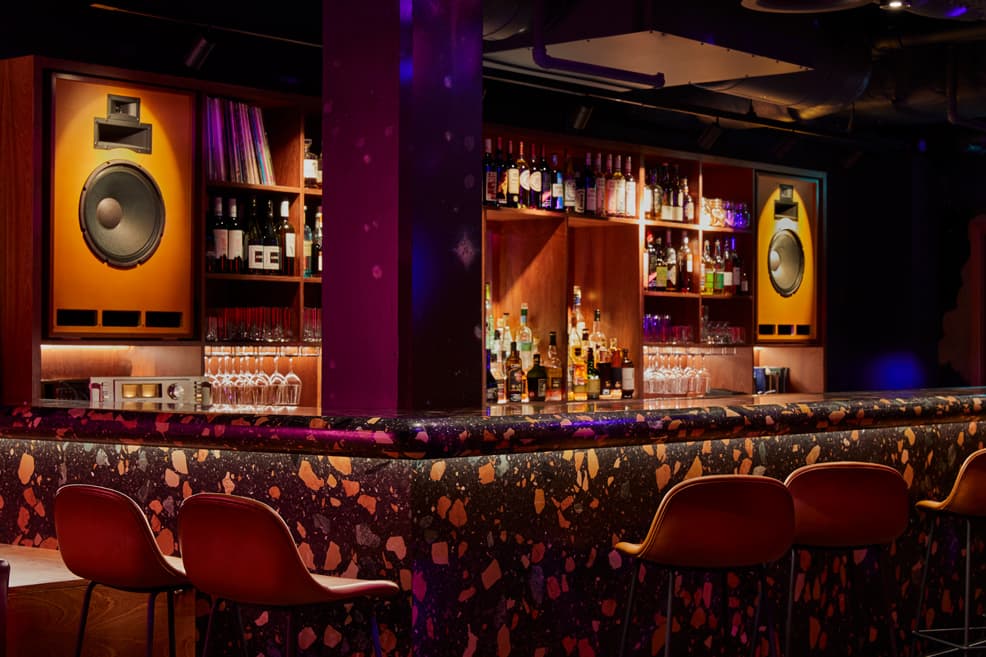Stylish bar with colorful terrazzo counter and shelves of spirits