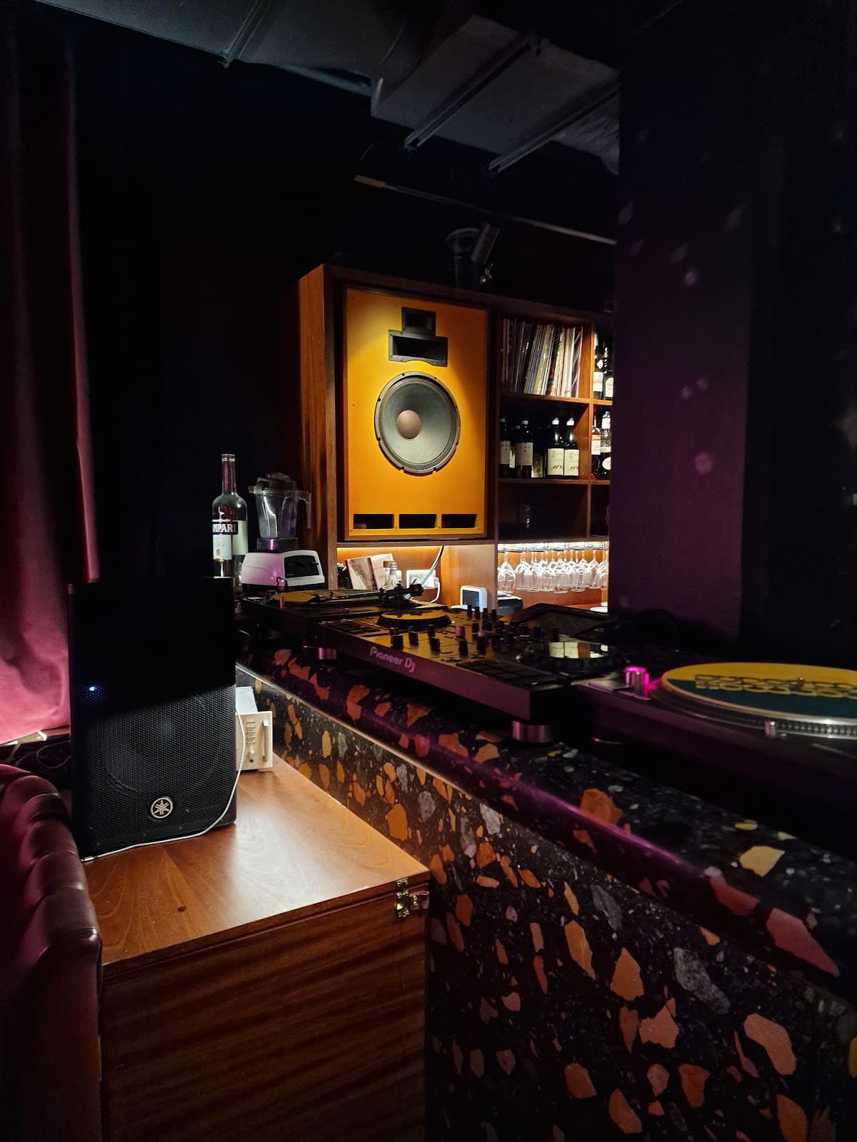Bar setup with DJ equipment and speaker at a cocktail venue in London