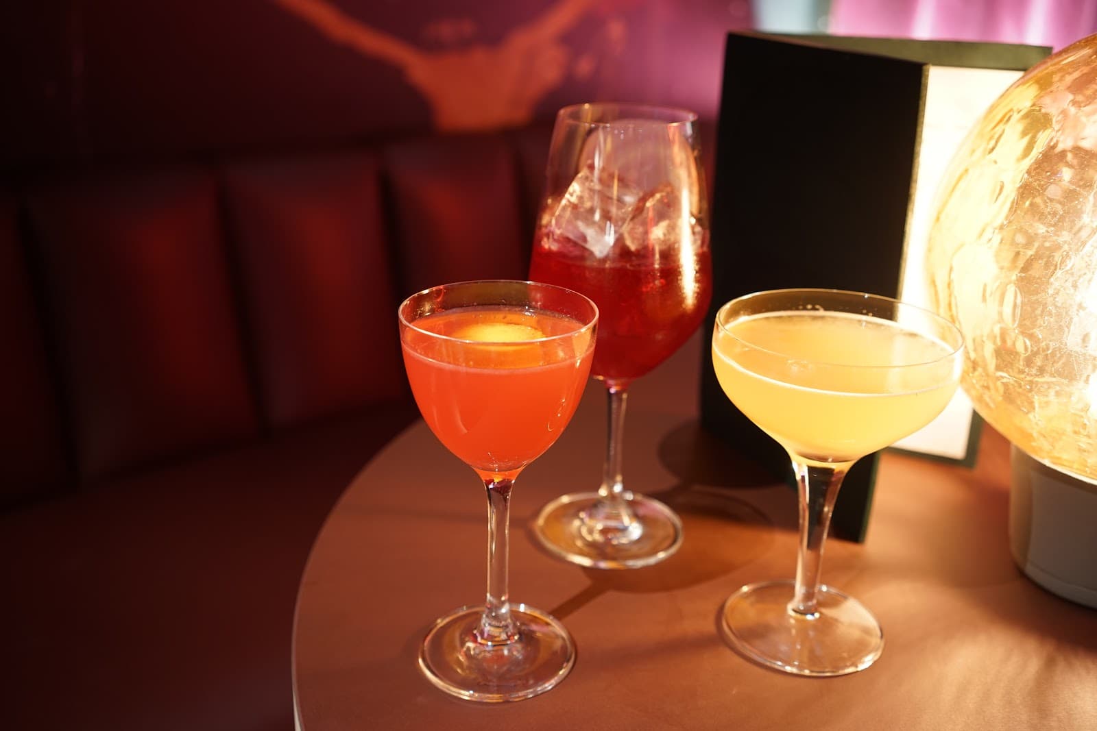 Three cocktails on a table with a warm glow background in London