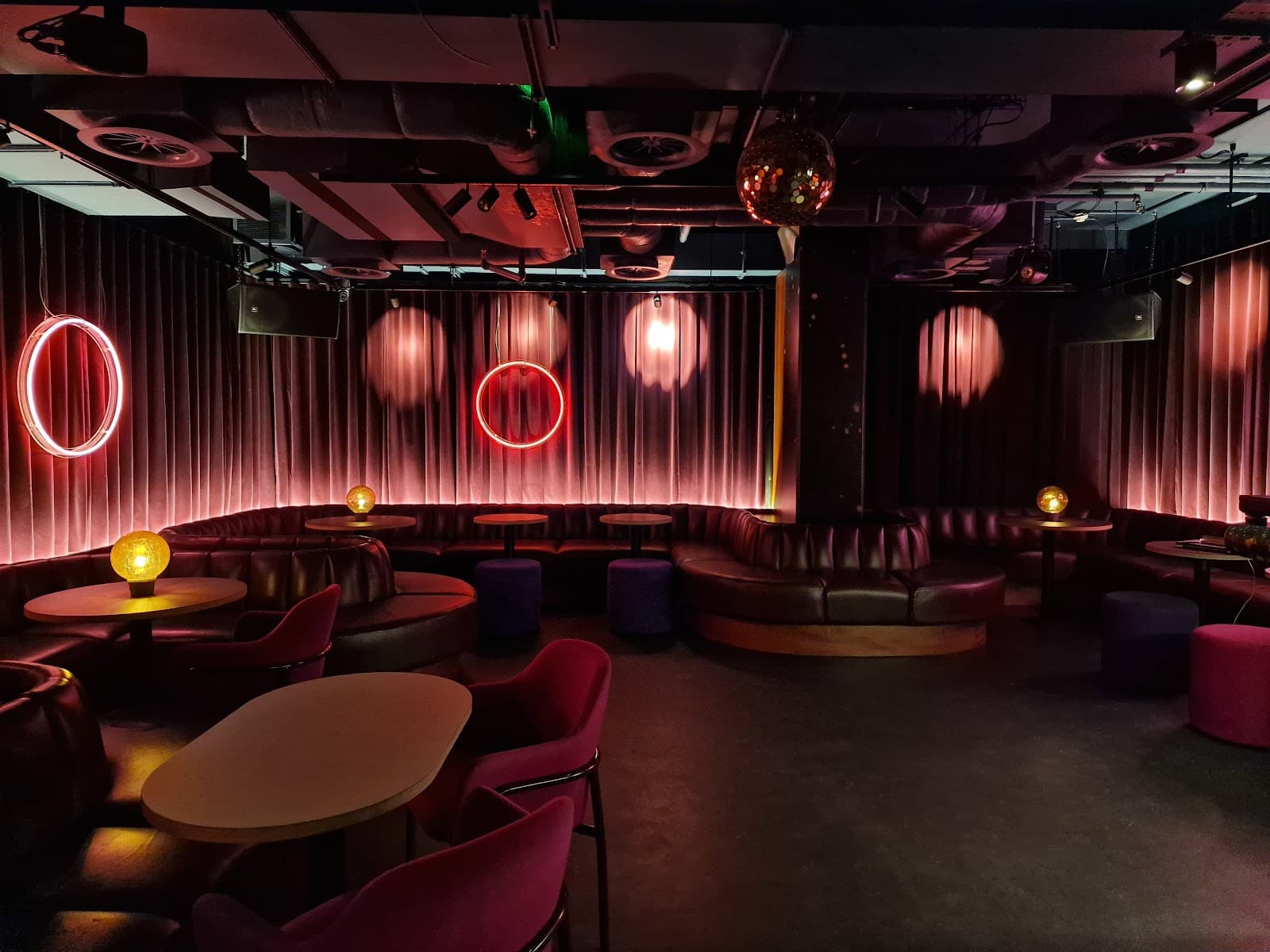 Chic cocktail bar interior with neon lights and circular seating in London