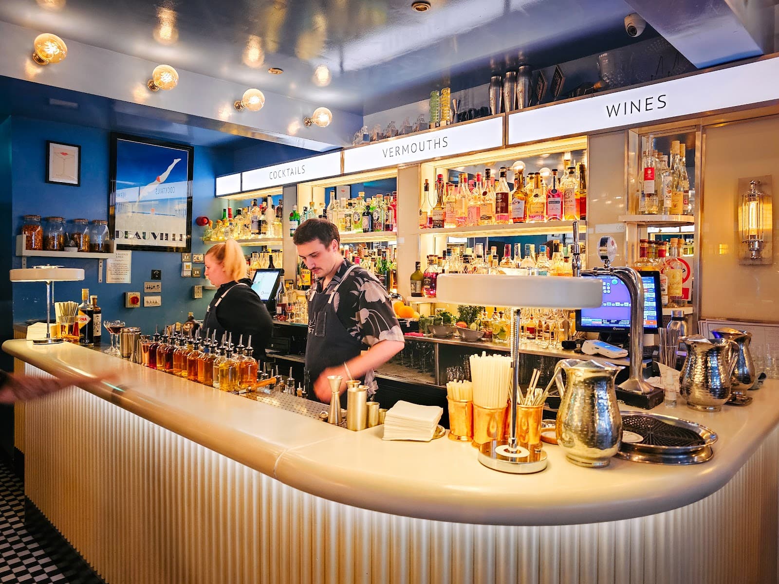 Well-lit bar with bottles displayed and bartenders preparing drinks in London