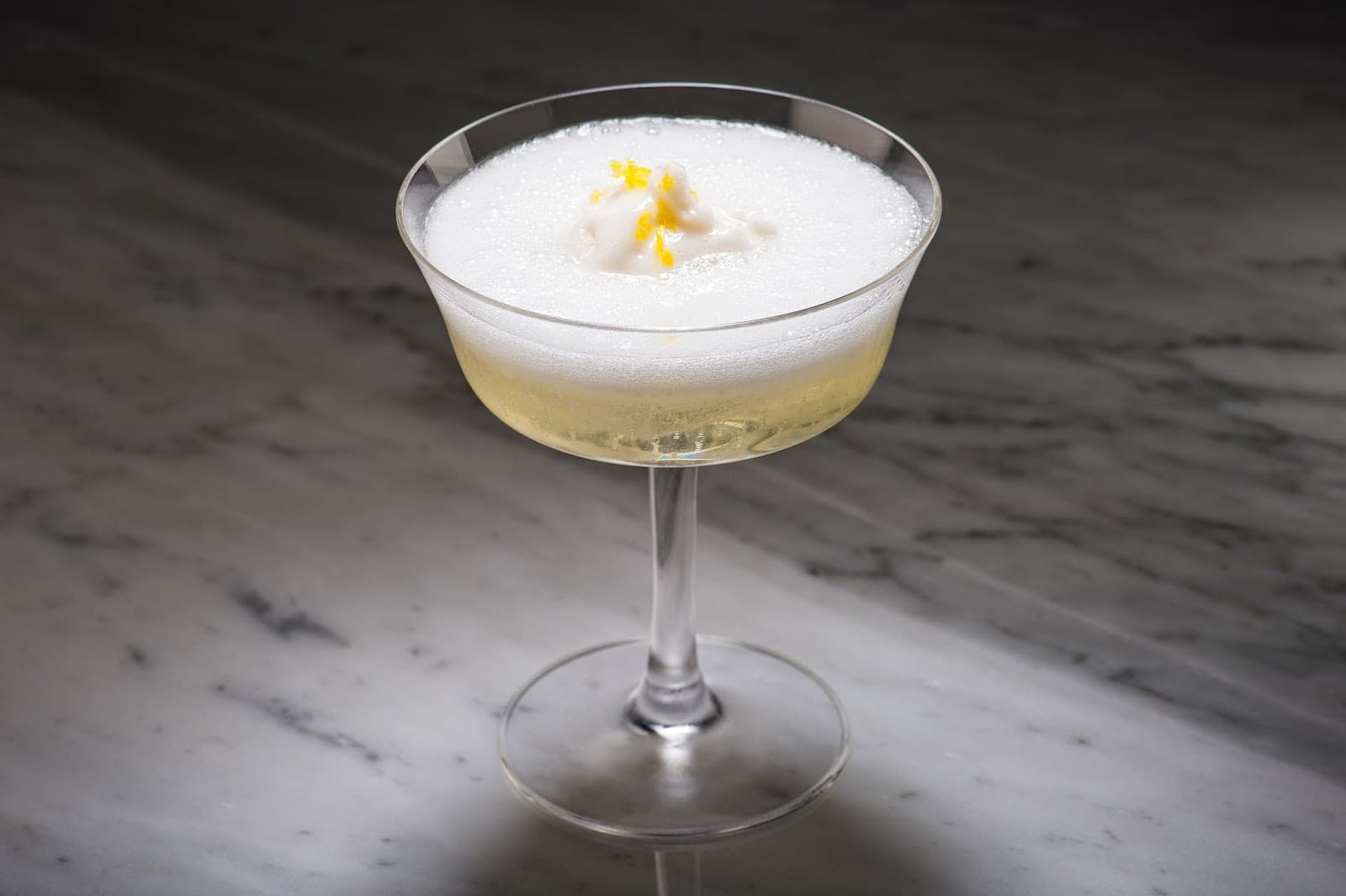 Elegant cocktail with foam garnish on a marble surface in London