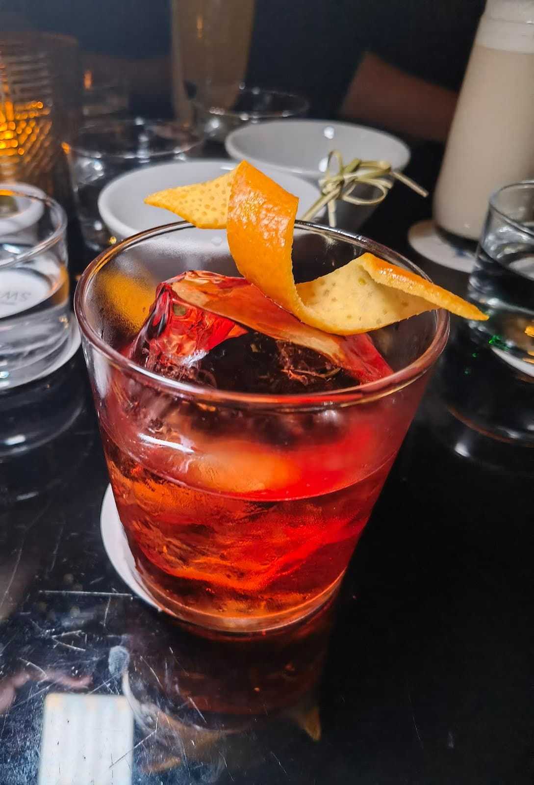 Close-up of a cocktail with orange peel garnish on a dark table in London