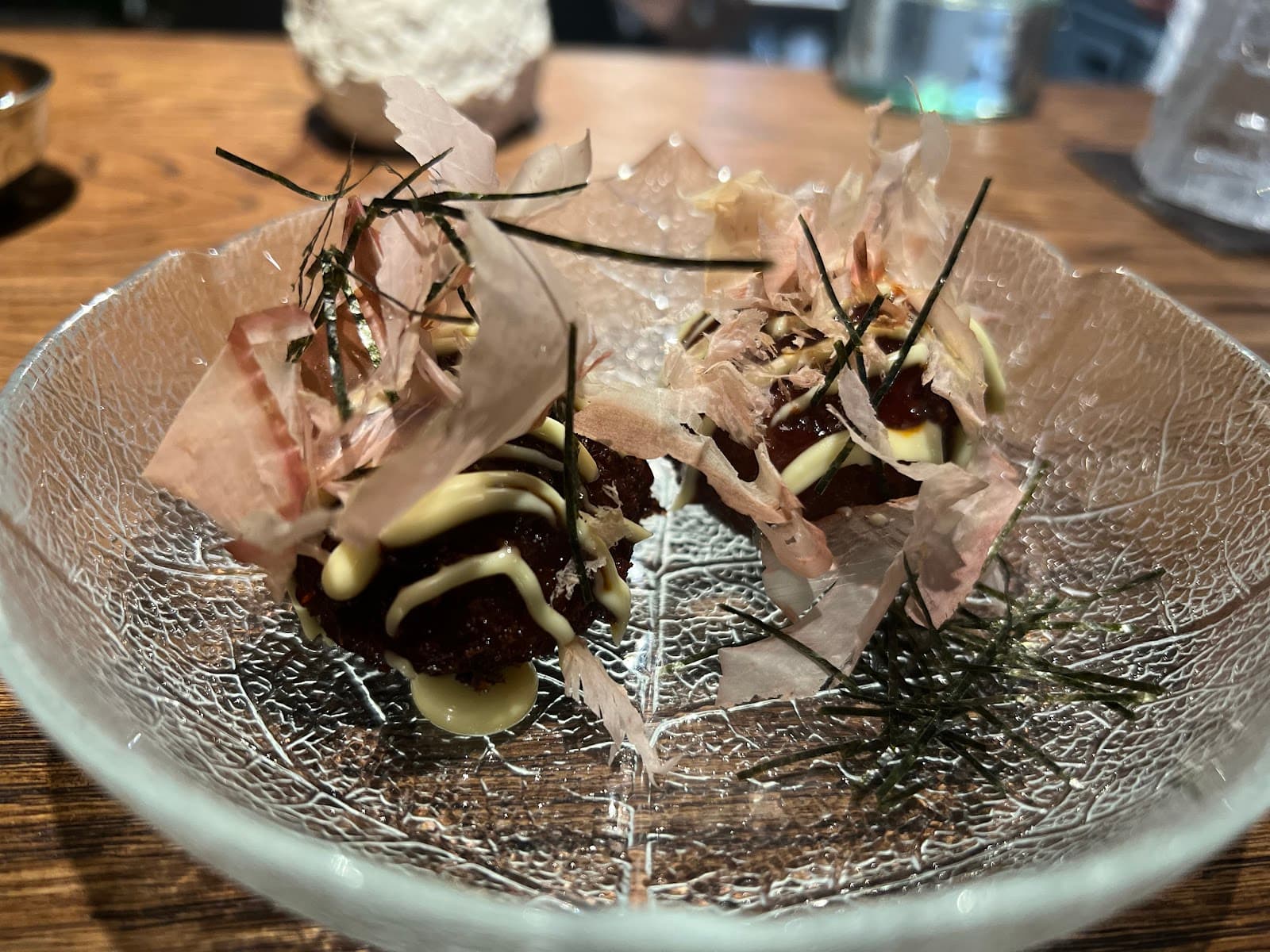 Close-up of a crafted dish on a glass plate with wooden table background in London