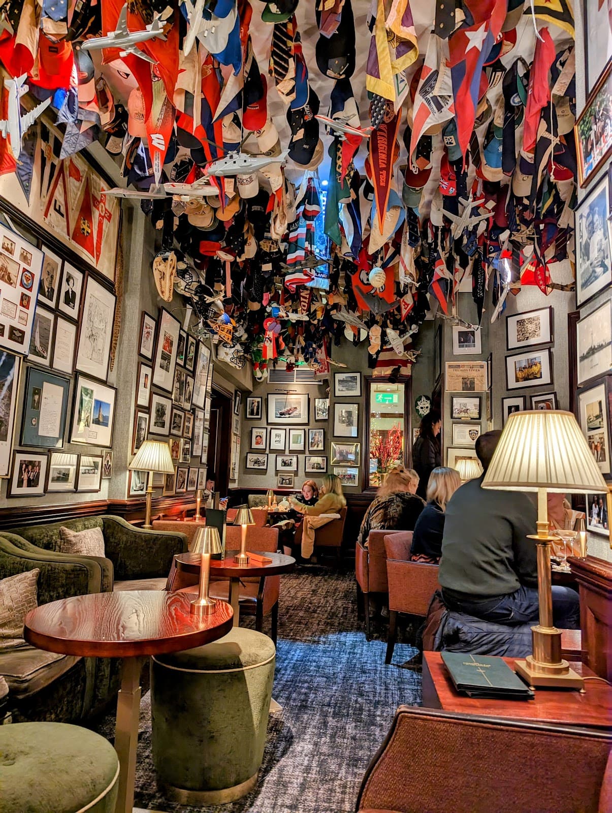 Cozy bar interior with hats hanging from the ceiling and framed pictures on the walls in London