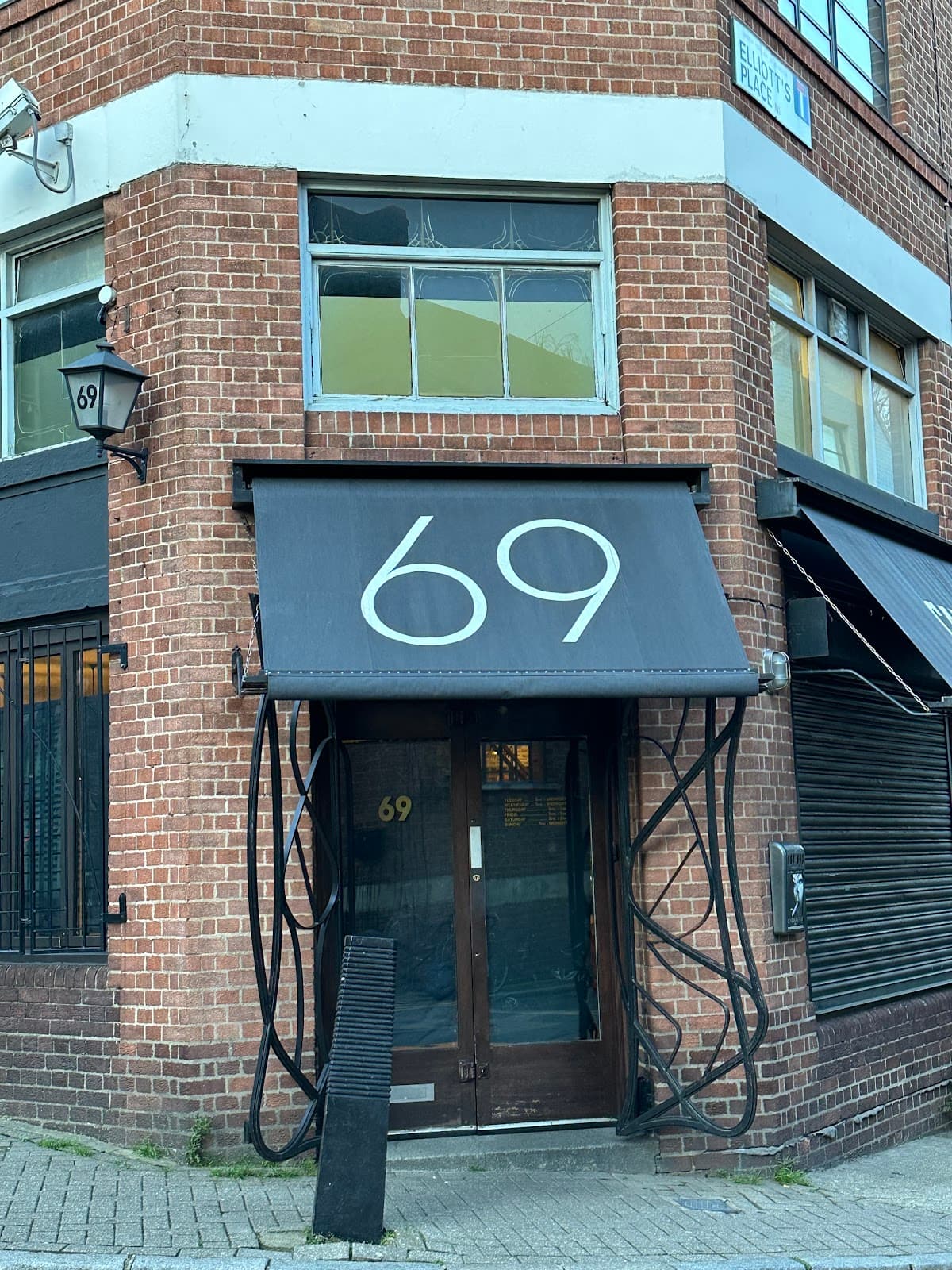 Brick building exterior with black awning showing the number 69