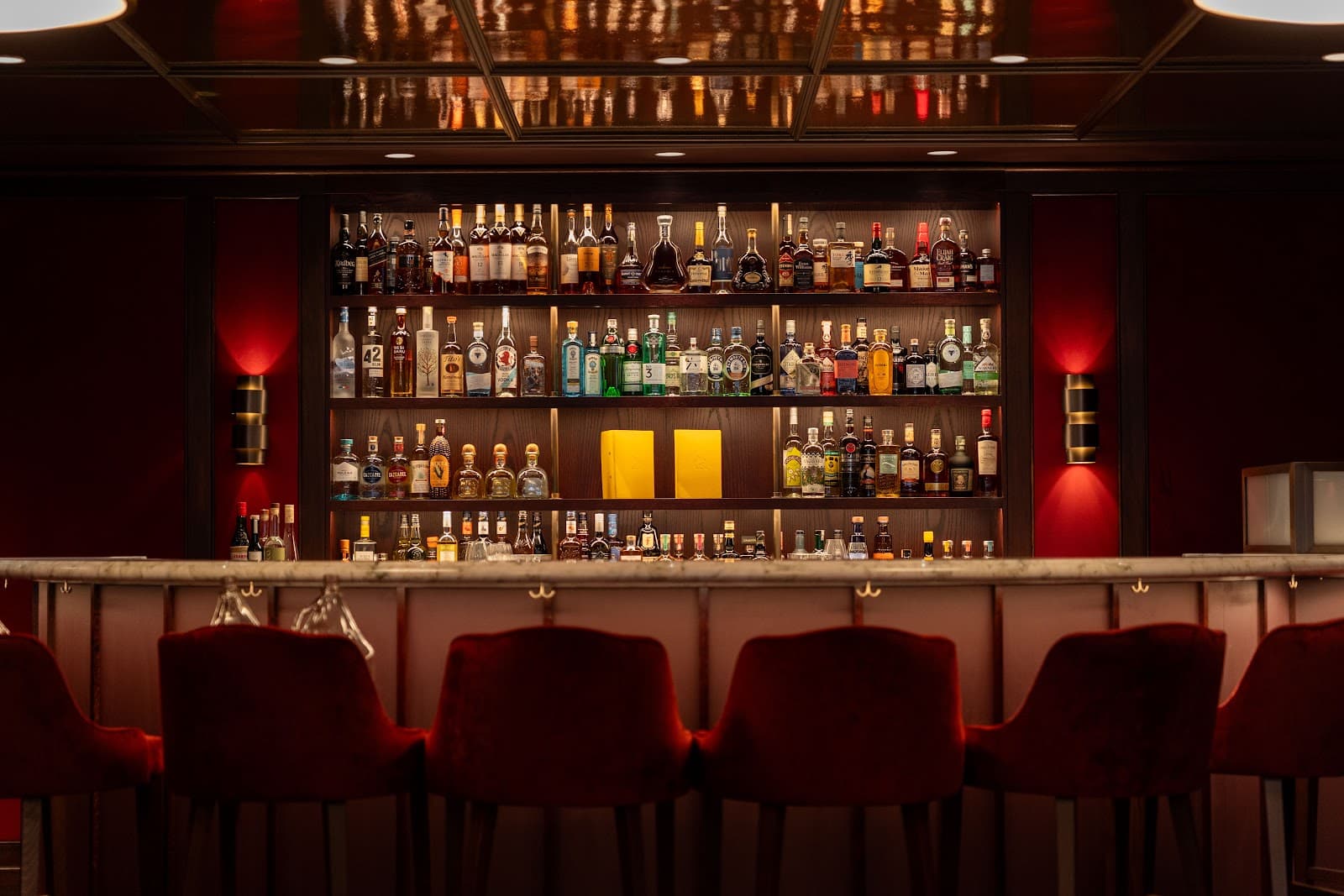 Elegant bar with red chairs and shelves filled with liquor bottles