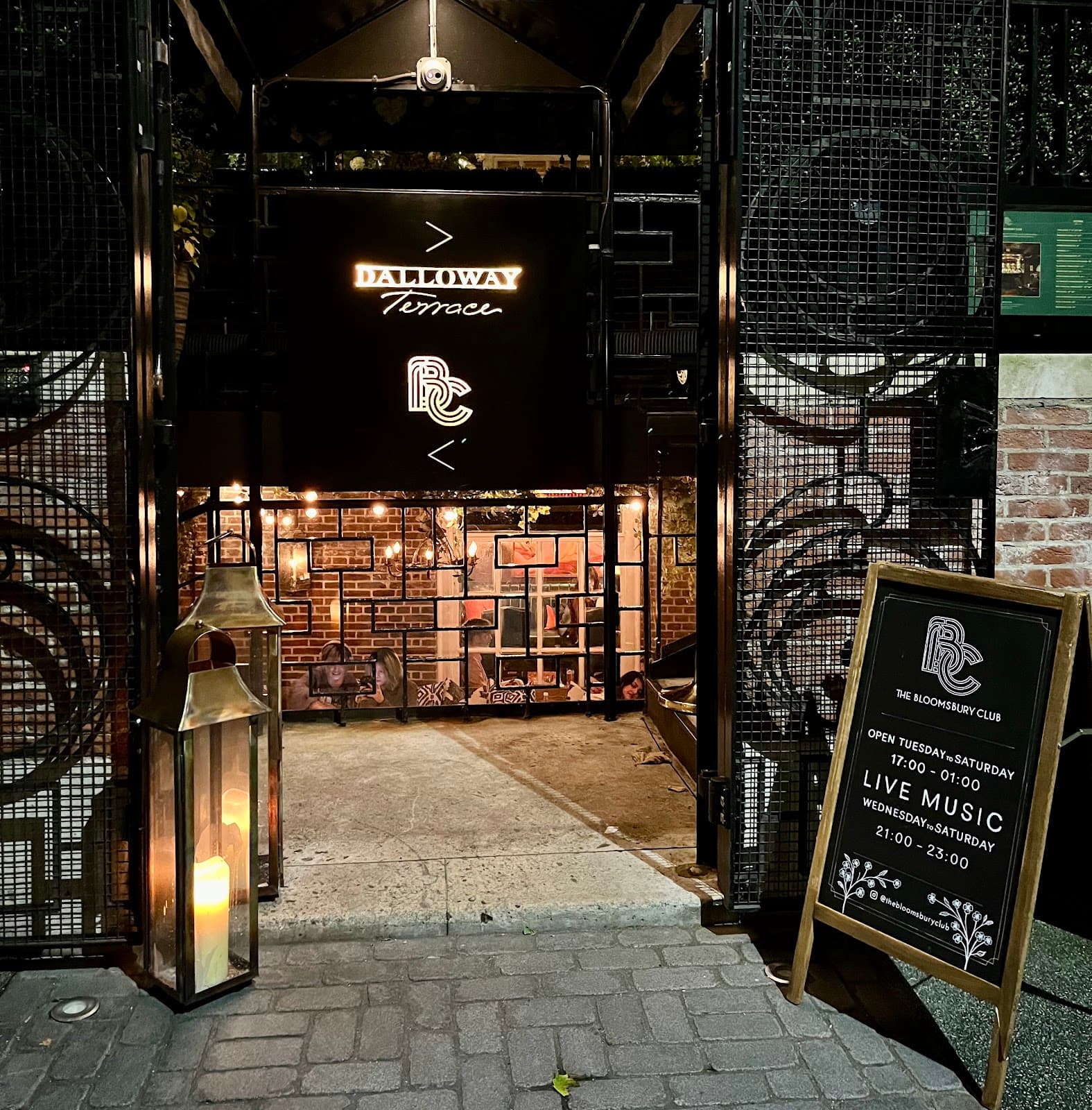 Entrance of Dalloway Terrace with lit sign and exterior decor at night in London