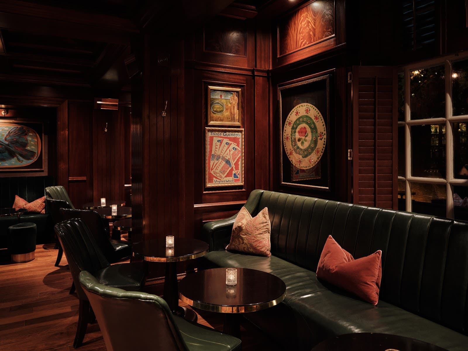 Cozy bar interior with green leather seating and framed artwork in London