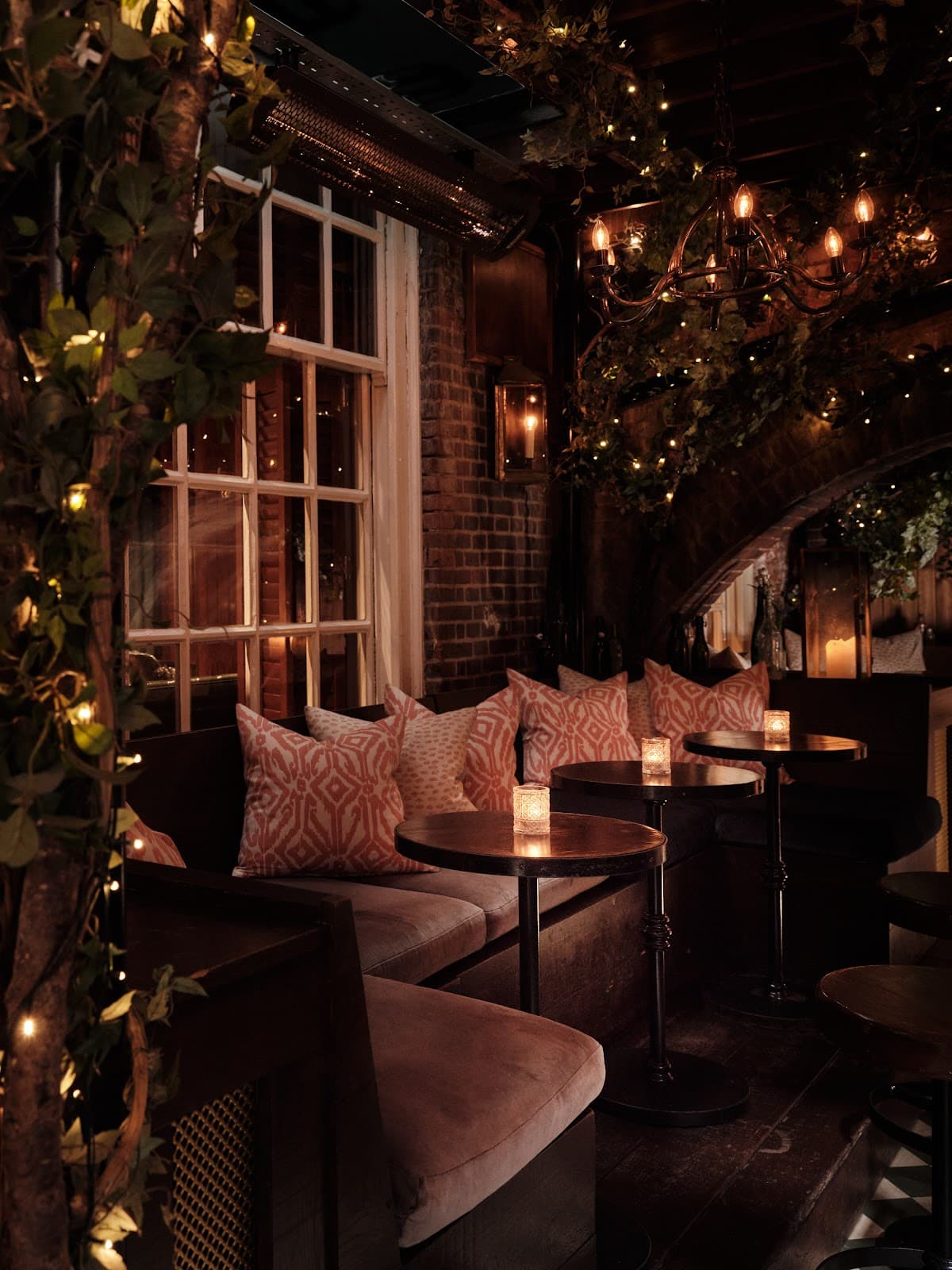 Cozy interior with candles, cushioned seating, and warm lighting at a cocktail bar in London