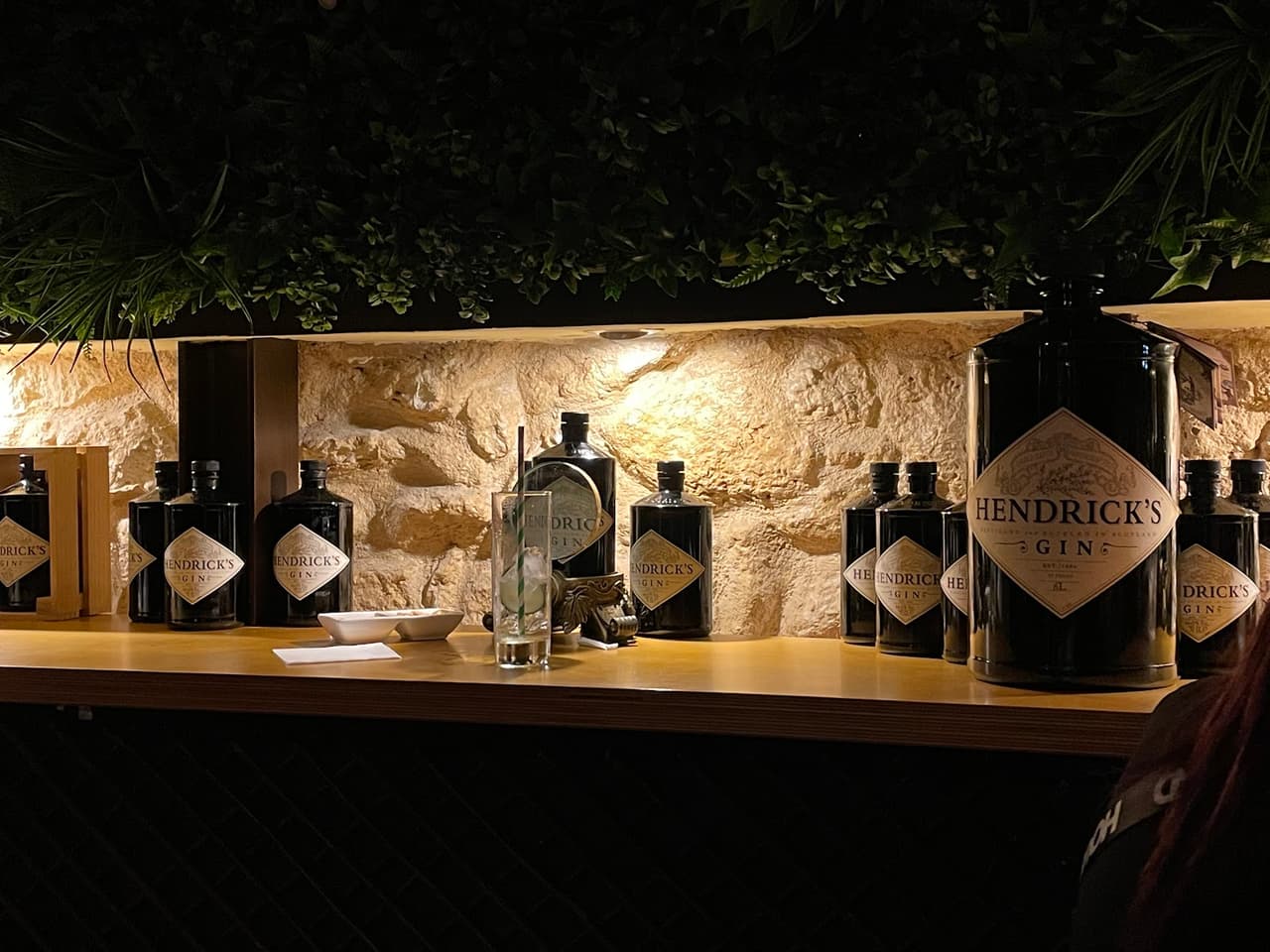 Bar counter with Hendrick's Gin bottles on display and a stone wall backdrop in Lisboa