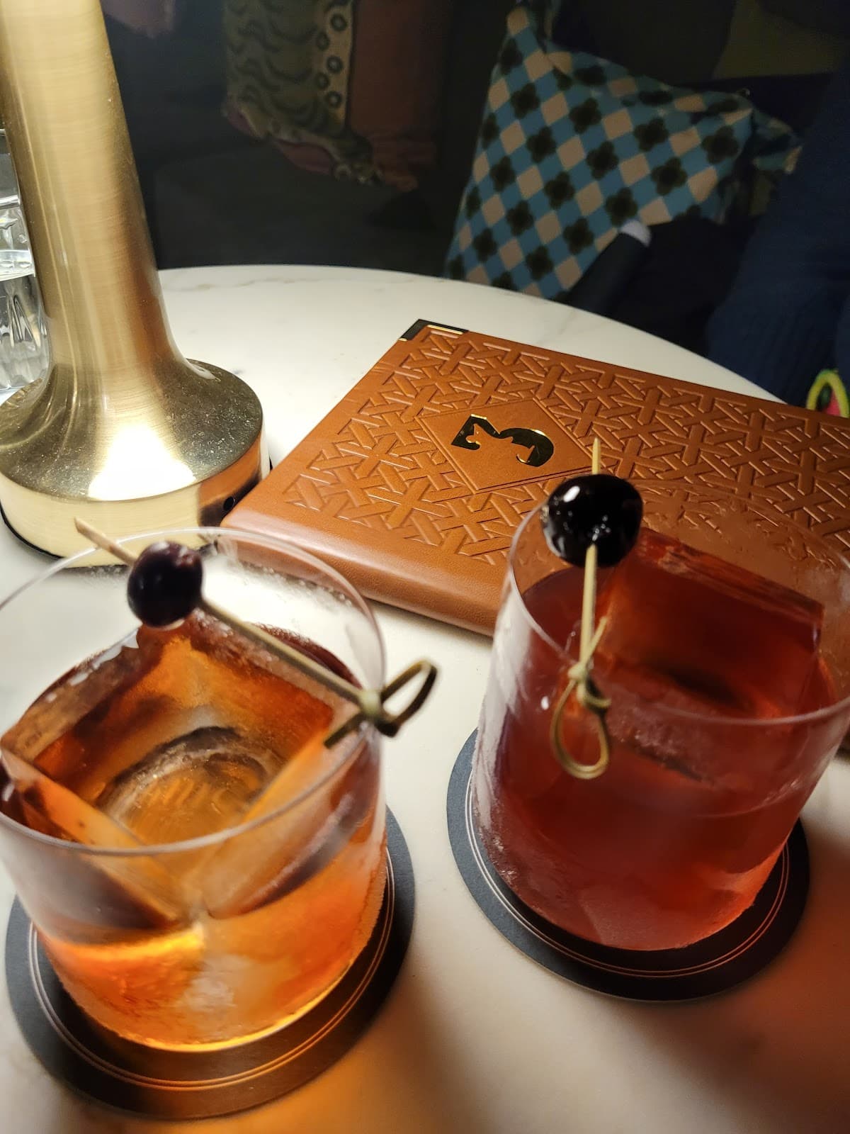 Cocktail glasses with large ice cubes and cherries on a table in Edinburgh