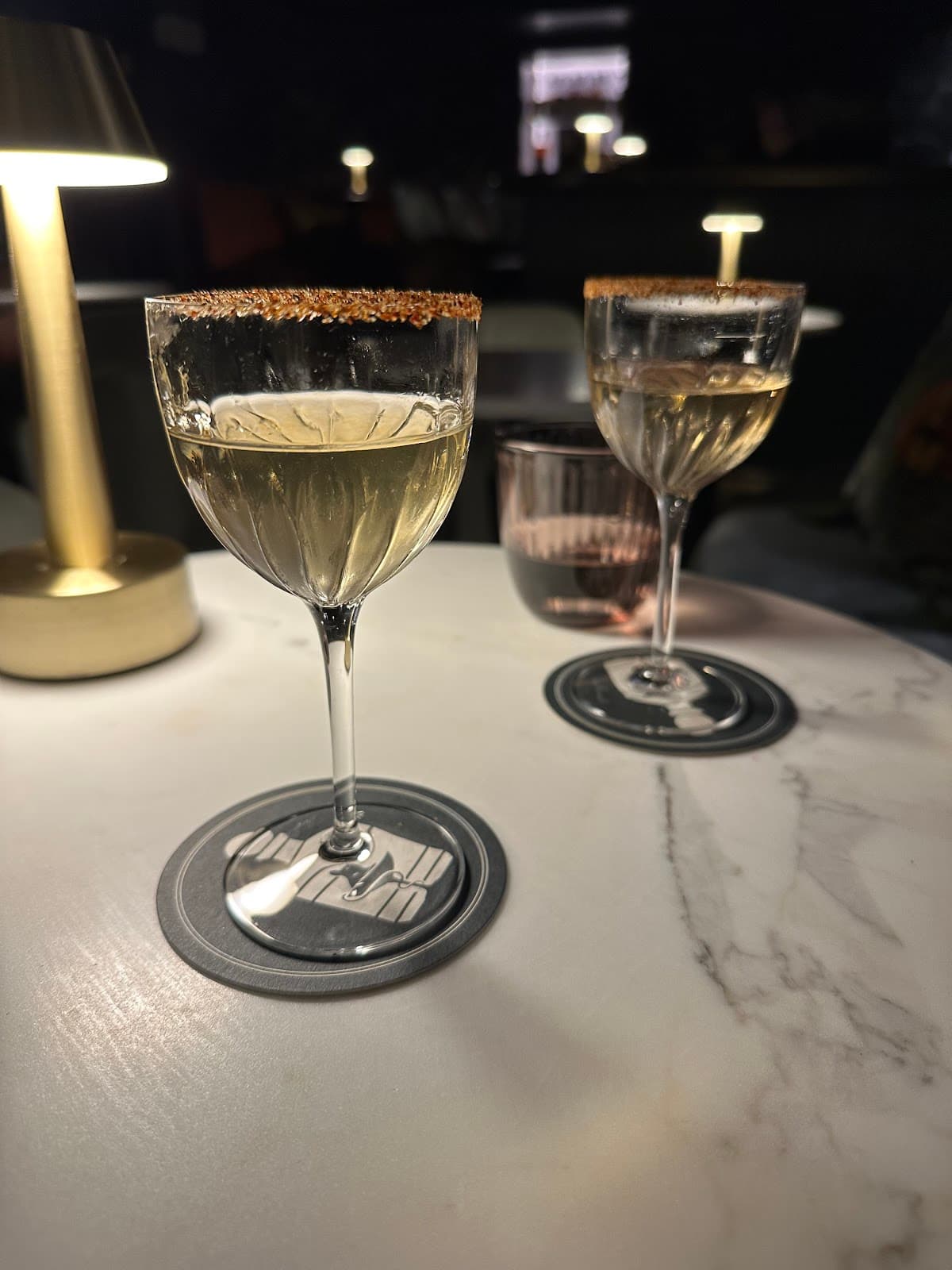 Close-up of two cocktails on a marble table under warm lighting in Edinburgh